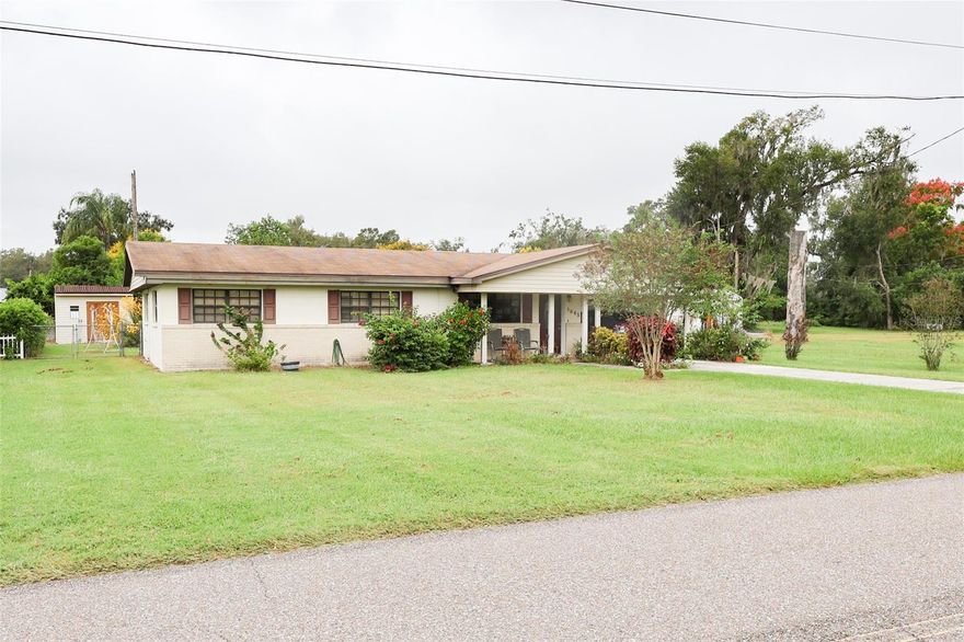 0.41 Acres....This solid concrete block home offers three comfortable bedrooms and a Jack-and-Jill bathroom that connects the primary bedroom to the main hallway for added convenience. An attached carport provides everyday ease, while the detached garage and workshop are ideal for projects and storage. There’s extra covered space on the side of the garage and a sunny greenhouse tucked just behind. The backyard is a gardener’s delight — fully fenced with vibrant flowers, a handy shed, and a charming chicken coop. A wonderful blend of function and Florida charm! The A/C unit was replaced in 2023.