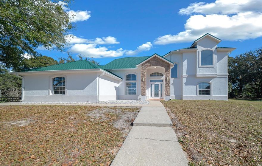 Spanning 16 acres, this picturesque horse farm is a true equestrian paradise. Nestled in rolling hills, it combines functionality with comfort, offering everything needed for horse training, boarding, or private enjoyment. Located in southern Marion County, only 15 minutes from the Florida Horse Park and I-75, 30 min from WEC and close to the Villages. This property is ready to go to work with upgrades including fencing with CenFlex,  2 Concrete Barns with a total of 20 stalls each outfitted with durable rubber mats to enhance horse comfort and safety. Led lighting  Energy-efficient, providing bright and even illumination, commercial-grade fans ensure proper ventilation and air circulation for a healthy barn environment. 4 additional wood barns (two are 12 x 24 and two 12x12) with 6 additional stalls designed for overflow or isolation, creating a total of 26 stalls across all barns. These rustic structures add a touch of charm while still providing practical horse accommodations. Among equestrian amenities are Covered Round Pen with a little sitting area on either side, ideal for observing training or giving lessons in any weather and a Horse Walker for cooling down or low-impact exercise. The 9 paddocks are spacious and well maintained, equipped with automatic waterers, ensuring horses stay hydrated and comfortable. The main barns feature a large, covered entertainment area with a modern outdoor kitchen and top of the line grill and a bathroom. After you’ve entered the property through the long driveway and passed the paddocks you now approach the custom-built home sitting high on a hill, a peaceful and elevated location with sweeping views of the surrounding pastures, creating a tranquil retreat at the heart of the farm. The open and airy 3-bed, 2-bath main home has interior high ceilings throughout with plenty of natural light, vinyl plank flooring, and hardwood floors on all bedrooms and stairs. Its kitchen includes custom cabinets, granite countertops, and a breakfast bar with a built-in wine rack. The Bright and Roomy Master Bedroom features a garden tub, his/her closet, extra-long vanity with double sink. Among improvements to the house within the last 4 years are New metal roof, separate HVAC for the master bedroom on the second floor, new well, pump and tank, gutters, Garage motor with remote control and Water Softener. Schedule your showing today.