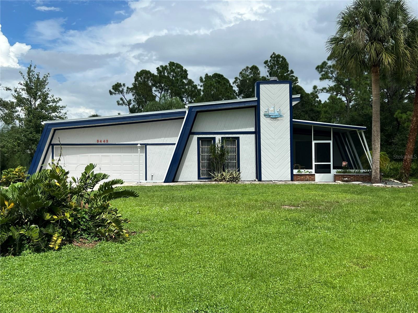 This One-Of-A-Kind Architectural Treasure has poured and stamped concrete or cast-in-place walls with metal perlines built to withstand hurricanes when constructed in 1987! The striking 3-bedroom, 2-bathroom, oversized 2 car garage home combines bold mid-century modern lines with timeless Florida charm and iconic Curb Appeal. From the moment you arrive, the home’s dramatic angled rooflines of the NEW Metal Roof, crisp white façade, and deep navy accents set it apart, making it a true showpiece in the neighborhood. Step inside to discover a spacious, light-filled layout designed for both comfort and entertaining. The open living and dining areas flow effortlessly, while large windows bring in natural light and showcase views of the lush greenery outside. Home boasts character and originality at it's finest and even has a brick fireplace in the living room to add to the welcoming feel and splendid charm of this home! The newly remodeled kitchen is ready to be decorated to your taste and offers plenty of cabinet space with NEW soft close cabinets and granite countertops. The bedrooms are generously sized, including a primary suite with ample closet space. The two additional bedrooms can serve as guest rooms, home offices, or creative spaces. The screened-in porches invite you to relax and enjoy Florida living year-round, while the yard offers endless possibilities for gardening, play, or future outdoor amenities. Additional highlights include an oversized two-car garage, unique architectural details throughout, and a location that blends privacy with convenience—just minutes from shopping, dining, and local parks. If you’ve been searching for a home that’s anything but ordinary, this is it. Don’t miss your chance to own a rare piece of design history that perfectly balances character, comfort, and potential. While viewing the home in person, you will be able to look through photographs of its unique detailed construction that is sure to Wow you and assure you of its strong construction that is meant to last!