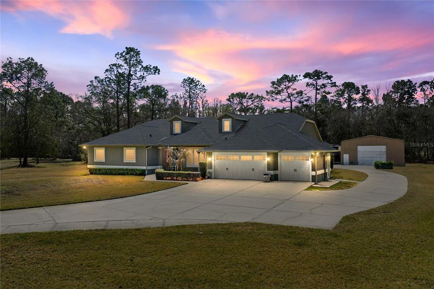There’s a certain ease to life when you have room to live it, and this Wesley Chapel 4 bedroom, 3.5 bath, 2 story home set on a full acre of land delivers that rare sense of openness from the moment you arrive. Shaded by mature trees and paired with an extended driveway, welcoming front porch, and a 2024 roof, the property sets the tone for a home designed to live big both inside and out. It offers not one but two major garage spaces: an attached 3 car garage plus an impressive 35' x 50' detached metal building with a 12' x 16' motorized door and lofted storage. Whether you collect cars, run a workshop, or simply crave room to create, it's all right here. Inside, a flexible, sprawling layout unfolds across the main level. The family room sets a warm tone with its stone-accented gas fireplace, tray ceilings, crown molding, luxury vinyl plank flooring, and seamless connection to the gourmet kitchen and dinette. The kitchen stands out as the centerpiece, an expansive culinary space with abundant cabinet storage, quartz countertops, breakfast bar seating under pendant lighting, a walk-in pantry, stainless steel appliances, a pot filler above the range, a reverse osmosis system at the sink, and an inviting eat-in dinette. Whether hosting gatherings or enjoying laid-back mornings, the setup creates effortless functionality wrapped in luxury. More intimate spaces sit nearby, including a formal dining room and a formal living room currently used as a game room, complete with a pool table that stays with the home. Multiple sliding glass doors in these spaces recess completely and open to the screened back porch, creating a true indoor/outdoor flow. Flexibility continues upstairs, where a 675 sq ft loft spans the entire second floor. With its own full bathroom, plush carpeting, and temperature-controlled storage room, the space is ideal for a second primary suite, media retreat, or multi-generational living. All traditional bedrooms remain on the first floor in a thoughtful split plan. The primary suite offers generous proportions, plush carpet flooring, sliding doors to the screened porch, dual walk-in closets, and a peaceful ensuite bathroom featuring a walk-in shower, jetted bathtub, water closet, and dual sinks with granite countertops plus a dedicated vanity seat. Nearby, a second bedroom works beautifully as an office or nursery with easy access to the guest half bath. Across the home, bedrooms three and four each include plush carpeting, large walk-in closets, and close proximity to the home’s third full bath. Every detail has been meticulously curated- from the surround sound system with speakers and individual volume controls in every room to crown molding, stone counters, upgraded flooring, and that incredible indoor/outdoor connection created by fully recessing sliders. Step outside to a screened porch overlooking a spacious yard with mature trees, a peaceful rural feel, and the expansive detached garage complete with a workbench and lofted storage. This stunning residence sits moments from local hotspots including The Krate, The Grove, Target, Tampa Premium Outlets, medical facilities including the soon-to-open Johns Hopkins Children’s Hospital, local restaurants, major highways for commuter convenience, and zoning for Cypress Creek Middle and High School. Homes with this ideal blend of land, flexibility, upgrades, and location rarely come to market. Call today to experience this exceptional residence for yourself.