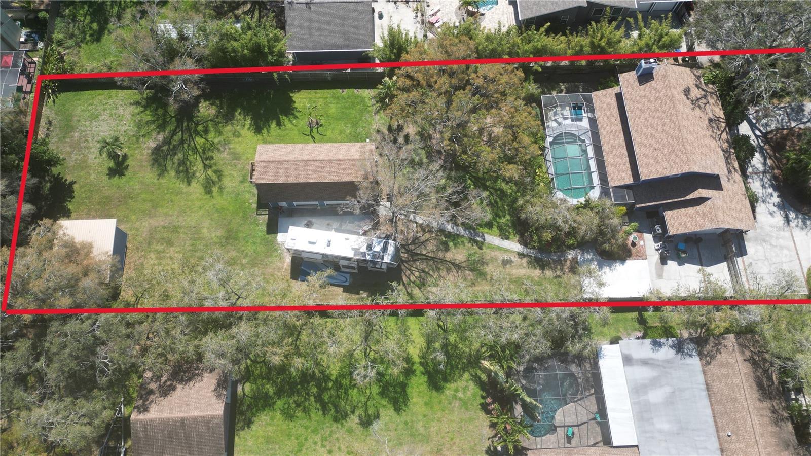 Motivated Sellers just authorized a significant price reduction!!! You can own almost 3/4 acres with a main house, a guest house, a barn used as a storage/workshop PLUS an extra land in the unincorporated Clearwater area, free of HOA or rental restrictions, and zoned for multi-family use up to 10 units. This property is located in a non flood zone and hasn't been affected by recent hurricanes. Centrally located in Pinellas County, it is close to the beaches, airports, shopping, restaurants and major roads & highways. Roofs on both houses were replaced in 2022. The primary residence features 2,642 sq. ft. of heated living space, with 4 bedrooms , 2.5 bathrooms & a 2 car garage. Highlights include a family room with a gas fireplace, formal dining room, and a large kitchen with a laundry room. Recent upgrades (2022-2024) encompass impact windows with lifetime transferable warranty, new window treatments, new HVAC units, pool equipment (pool pump & assembly, salt generator & pool heater), kitchen appliances, and bathroom renovations. Downstairs, you'll find travertine flooring and a staircase leading to the upper-level bedrooms. The expansive kitchen boasts a coffee bar, wine bar, ample solid wood cabinetry, and a breakfast bar. From the large family room with a gas fireplace, French doors open to a screened-in salt pool area with a large patio, featuring an outdoor bar and TV, along with ample space for lounging and sunbathing. The second house/guest house features two garages, one converted into an office with a full bathroom and laundry room downstairs. Upstairs, you'll find about 1,000 square feet of living space with a balcony. The property has a fully irrigated deep well system and it is beautifully landscaped for privacy. A sidewalk leads from the main house to the guest house. In the corner of the lot, a barn has been converted into a workshop and storage space. There are no restrictions on having a boat, RV, or any other additional vehicles behind the newly replaced wooden fence with a privacy gate.Whether you're looking for a move-in ready multi-family property or an income-producing investment in the heart of Pinellas County with room to grow, this is the one.