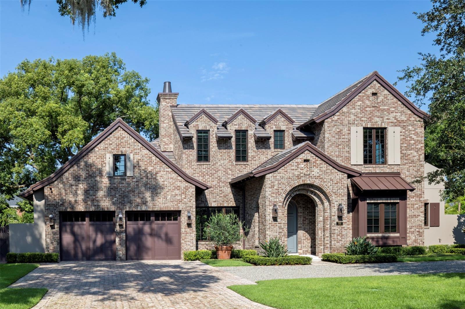 Welcome to 702 Via Bella, an impressive 2025 English Cottage Estate by Floridian Custom Homes that captures the essence of timeless architecture exemplifying transitional elegance and true artisan craftsmanship. Located in one of Winter Park’s most desirable residential corridors, warmth & beauty abound in this 4 bedroom, 6 bath residence spanning 3,720 sf conditioned and 4,535 sf total under roof, offering layered living, artisanal materials, and a modern infrastructure. Upon entry through a solid mahogany front door, warmth and beauty abounds with Botticino limestone flooring enhanced by a textured finish, extensive custom millwork, and an abundance of open concept living areas. Coffered ceilings and recessed WAC lighting create a gallery-like ambiance, enhanced by natural light from insulated casement windows. The central living space integrates with the dining area and designer kitchen, which features custom cabinetry by Grit & Grain, leathered Taj Mahal quartzite surfaces, and chef-grade appliances: a La Cornue 43-inch gas range with McGurken hood, Thermador 30-inch refrigerator and freezer columns, and Bosch dishwasher. The kitchen transitions into a walk-in pantry with cabinetry, quartzite, dual refrigeration drawers, and a dedicated ice maker. An oversized mudroom, finished with hardwood built-ins, offers expanded storage and functionality. The first-floor primary suite is privately positioned in its own wing and finished with wide-plank European white oak flooring by Forrest Accents, a walk-in closet with textured built-in systems, and a spa bath with natural stone countertops, Rohl polished nickel fixtures, a marble-tiled floor and shower, and a frameless glass enclosure. All doors are solid-core with Emtek hardware. The library, located near the front of the home, offers a quiet retreat with matching oak floors and custom casements. A solid wood staircase leads to the second level living areas including a lounge flex space. There are 3 additional bedroom suites, each with en-suite baths, offer porcelain flooring, frameless glass shower doors, brushed quartz and dolomite vanities, decorative lighting, and built-in closet systems. Additional features include CAT-5/6 wiring, Sonos-integrated speakers, lighting automation via the Lutron RA-3 smart system, and pre-wired home security with digital camera ports at key access points. Thoughtfully placed access points from the primary suite and kitchen wing lead to a fully enclosed backyard retreat, where mature landscape design by Signature Landscape frames a private outdoor living sanctuary. A Roman-inspired cabana with grand ceilings and exposed beams anchors the outdoor entertaining space, flanked by a fully tiled (50k upgrade) saltwater pool featuring therapy jets, LED-lit bubblers, a dual-skimmer system, automated controls via a Jandy heat pump, and a Paramount self-cleaning system. Clay brick pavers and landscape lighting define the walkways as well as front entry driveway. This home was constructed with a stem wall foundation, concrete block first-floor exterior walls, and 2x6 second-floor framing for structural performance along with spray foam and sound mat insulation between floors ensure comfort and acoustic separation. Finished in a palette of clay brick and hand-troweled stucco, the home is crowned with architectural tile shingles and custom metal accents. Eight-inch half-round gutters, aluminum downspouts, and engineered drainage ensure long-term exterior performance.