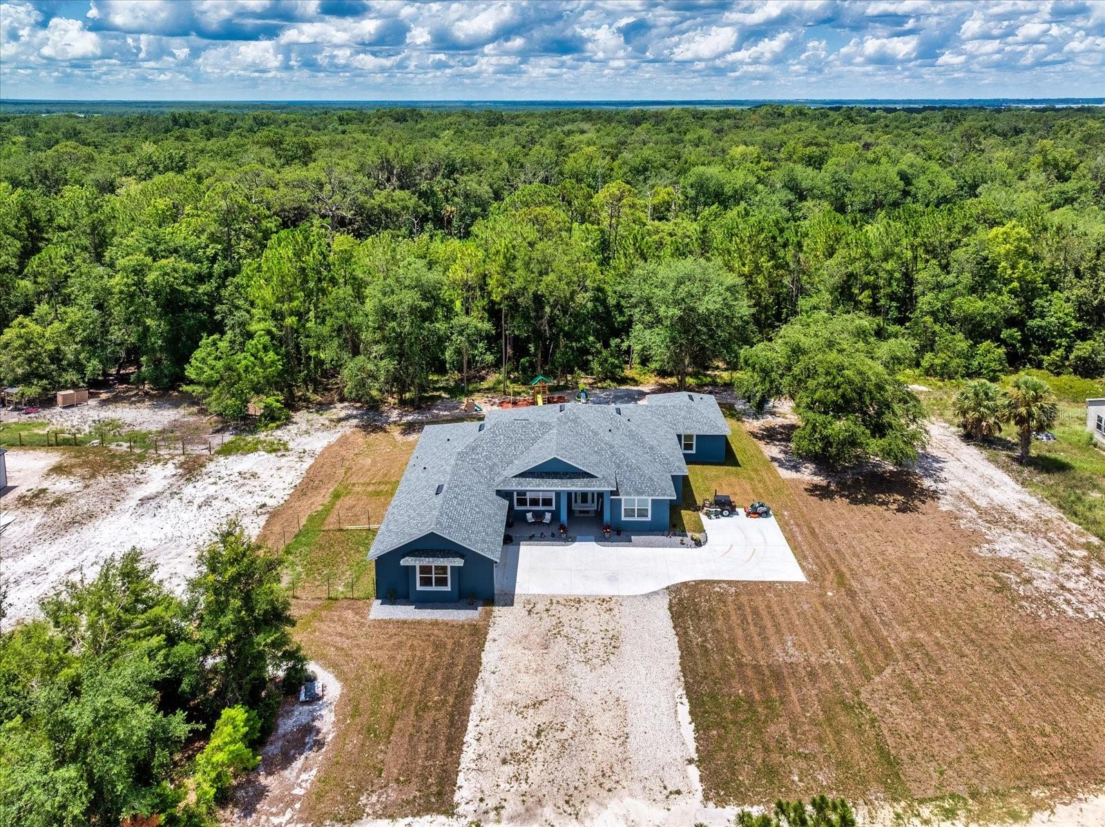 Welcome to 1845 Springhead Dr, located on a serene and scenic 2.5-acre lot in Enterprise. This charming residence was built in 2025 by the leading custom home builder, American Family Homes, and offers the perfect blend of comfort and tranquility, featuring 5 bedrooms, 4 bathrooms, an (IN-LAW SUITE), and a thoughtfully designed open floor plan that makes the most of its generous square footage. When entering the inviting entryway, you’ll be greeted by beautiful plank tile, soaring high ceilings, and an inviting living space abundant with natural light. The well-appointed kitchen will be ideal for entertaining and boasts quartz countertops, a farmhouse sink, 36” cabinets with crown molding, recessed lighting, and an oversized island with a built-in microwave and bar stool seating. You’ll love this home's split floor plan, including a lavish master bedroom featuring a spa-like bathroom suite complete with a spacious walk-in closet, dual granite vanities, and a massive walk-in shower that will take your breath away. The in-law suite is ideally situated on the opposite side of the home and has its own living space, complete with a kitchenette and master bath featuring a walk-in closet, dual granite vanities, and a luxurious walk-in shower with a frameless glass enclosure. There are also 3 additional bedrooms on this side of the home that share 2 additional guest bathrooms complete with modern fixtures and a shower and tub combo. Let's not forget the expansive lanai located off of the great room and in-law suite that will be ideal for outdoor gatherings and relaxation. This home also offers a water treatment system, double-pane windows, a fenced-in area for pets, and a transferable builder's warranty. With no rear neighbors and easy access to nearby trails and Lake Monrow, this home offers a lifestyle that’s both peaceful and convenient. Don’t miss this opportunity to own a piece of old Florida charm in beautiful Enterprise. Book your private showing today!