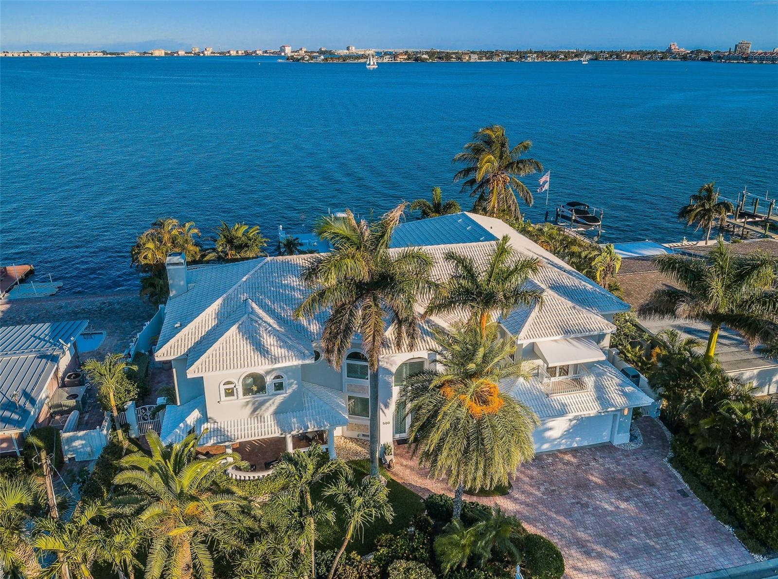 SITUATED IN THE HEART OF ST. PETE BEACH, A STUNNING AND RARE WATERFRONT ESTATE THAT REPRESENTS THE BEST OF BOATING AND THE BEACH! Located in exclusive Brightwater Beach Estates, this luxurious residence offers a dazzling floor plan complemented by prodigious columns, fluted moldings, high ceilings, travertine flooring & elegant window treatments (originally built in 1959, the home was extensively rebuilt in 2000). A 20ft high entryway transitions to a 520sqft foyer overlooking your magnificent pool deck and waterfront. Step up to an unforgettable living environment designed to maximize the quality of your waterfront experience, with a wide great room featuring captivating waterviews. Step out to the impressive, 50ft-wide covered entertainment balcony and take-in 2 miles of sweeping vistas of Boca Ciega Bay. You’ll love the commanding views of the 270sqft open, upper-level sundeck. The sumptuous contemporary chef’s kitchen boasts white coastal cabinetry, blue flake granite counters, large breakfast bar, generous center island prep area, hi-end SS appliances, 8-burner gas cooking, built-in refrigeration, 2 ovens & 2 dishwashers. The graceful, private owner’s suite contains a sizable sitting area, large walk-in closet w/closet system and access to 2 waterfront balconies. Owner’s bath is an inspiring, pampered retreat – with jetted Jacuzzi spa, dual vanities and an exceptional glass shower enclosure. All bedrooms are oversized and all baths enjoys lavish appointments. The covered 700sqft “U-Shaped” lower-level entertainment deck provides numerous dedicated sitting areas, while the fabulous pool deck oasis features a dazzling pebbletec pool, elevated hot tub & full pool bath. Not to be outdone, the superbly constructed composite boat dock includes a huge sitting area, weatherproofed pilings, weatherproofed electrical/water/fixtures, 13K lift, moorings for a cruiser & stepdown area for paddleboards/kayaks. The grounds are lushly & beautifully landscaped, and meticulously maintained on all sides of the home. Elevator, tankless hot water heating, water softening and many, many extras that must be seen to be appreciated. Breathtaking water views by day, stunning moonlit waters by night with the sparkling lights of St. Pete Beach & Isla Del Sol in the near distance. By any definition, a true waterfront treasure! An easy walk to the beach, dining, shopping and entertainment of one of America’s premier beaches. Dimensions are estimates, buyer to confirm. Ask about assuming $1.45 mill at 2.75%.
