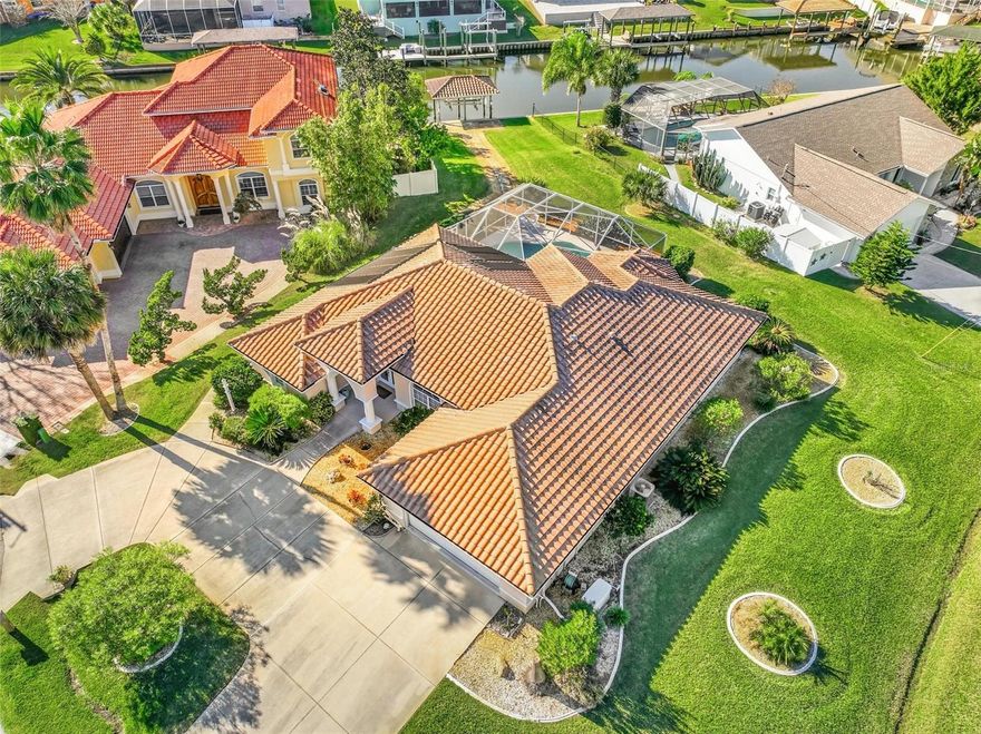 Tucked away on an oversized corner lot along a peaceful saltwater canal, this impeccably maintained Palm Coast home offers the ultimate Florida waterfront lifestyle. From the moment you arrive, the expansive circular driveway and pride of ownership set the tone. Step inside and you’re immediately welcomed by soaring ceilings, abundant natural light, and a stunning sightline straight through to the sparkling pool beyond. The formal living and dining rooms flow seamlessly into a beautifully updated kitchen featuring white cabinetry, a striking granite waterfall island and matching backsplash, an eat-in nook, and an inviting family room with a fireplace and walls of windows and doors opening to the covered lanai and pool. Designed for both privacy and comfort, the primary suite occupies its own side of the home and includes a generous sitting area or office, French doors to the lanai, walk-in closets, and a fully updated spa-like bath with double sinks, soaking tub, walk-in shower, and private water closet. Guests enjoy their own wing behind a pocket door with two oversized bedrooms and a large bath complete with soaking tub and shower, all filled with natural light. Outside, relax by the pool, entertain under the covered lanai, or head out for a short boat ride to the Intracoastal from your covered boat lift with electric and water—fully functional and ready to go. With a tile roof, full-house generator, sidewalk wrapping the home, and a home maintained to perfection, this property is clean, move-in ready, and offered as-is for its next owner to enjoy.