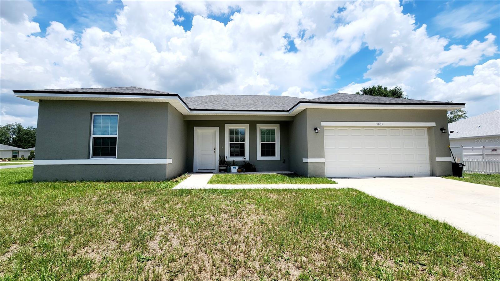 This house located in Ocala’s Marion Oaks subdivision was built in the winter of 2023, and has 4 bedrooms, 2 bathrooms, and a 2-car garage, with an open-concept floor plan. This 1,580 square feet home is built on a solid concrete foundation and finished with ceramic tile flooring. For daily living done easily and enjoyable you’ll be strategically located within a mile of amenities such as a grocery store, pharmacy, gas station, and local eateries. At just over a quarter of an acre, the openness of the corner lot is certainly part of the home’s appeal. The kitchen is designed in contemporary style with 42-inch rich espresso cabinets and speckled granite counter tops. But the kitchen isn’t just a style statement it’s also ready for occupancy or tenant move-in with all major kitchen (stainless steel) appliances equipped: range, microwave, refrigerator, and dishwasher. The functionality continues at the kitchen island, with undermount sink and integrated disposal, providing more space for cooking, prepping and cleanup. Tucked away for privacy is the laundry room with a shelf mounted above the washer and dryer, also included. The primary bedroom has a walk-in closet and en-suite bathroom. The primary bathroom features a double vanity with a granite countertop. Also, a beautifully designed walk-in shower with sliding glass door, marble-patterned tile extending up to the ceiling with a decorative accent band of mosaic tiles across the center, shower head with multiple nozzles, and a grab bar for added safety. All windows come equipped with installed blinds. The home includes a water purification system that serves the entire house for overall health and wellbeing to the homeowner.