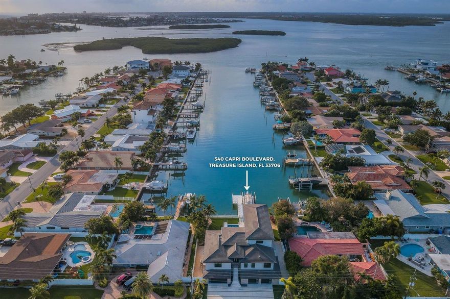 Presenting a truly exceptional masterpiece of concept and design, behold this breathtaking custom-built tri-level WATERFRONT residence spanning an impressive 3,794 square feet. Meticulous craftsmanship and cutting-edge aesthetics are seamlessly blended in this architectural marvel.  Seamlessly blending indoor and outdoor spaces, an exquisite foyer with 14' ceilings and 40-inch porcelain tile floors welcomes you into a world of panoramic views over Boga Ciego Bay's intracoastal waters. With 84' of waterfront, sailboat water access, and a private composite dock boasting a 20,000 lb. boat lift, electrical and water supply, you can reach the Gulf-Of-Mexico in just a 5-minute boat ride. The intelligently designed PebbleTec heated infinity saltwater pool creates a mesmerizing effect, seemingly cascading into the waterway, and can be controlled effortlessly using a smart device. The great room, illuminated by natural light, features a "smart home" with a minimalist built-in media center, electric fireplace, mounted TV, ceiling fan, and surround sound. It effortlessly flows into the dining room and kitchen, where the dining room overlooks the intracoastal waterway and features a chandelier and remote shades. The culinary kitchen boasts high gloss custom cabinets, stainless Miele/Subzero appliances, an espresso maker, warming drawer microwave, 5-burner gas range, and double ovens. A coffee and wine bar complements the large center island with a waterfall marble top, high top bar, and three pendant lights. Enjoy breathtaking views from the 300sqft covered shell stone tile deck/patio, perfect for entertaining and capturing the beauty of Boca Ciego Bay's waterways. The residence also features a 3-level elevator, an owner's retreat on the third floor with waterfront views, a custom designed closet, and a sumptuous master bath with a 2-sink vanity, walk-in rain shower with wand and multi-nozzle body sprays, and a Toto Noerest toilet system. The additional bedrooms are equally impressive with oversized layouts, walk-in closets, fans, and luxurious full baths. The second bedroom provides private balcony access to the pool deck, overlooking the waterfront. Other highlights include an interior laundry room, fenced backyard with artificial turf and a putting green, a covered lower-level waterfront deck, a 6-car garage with extra storage, a circular drive, epoxy garage floors, and xeriscape landscaping. Within walking distance, you'll find Treasure Island Beach, as well as a variety of restaurants and shopping options.