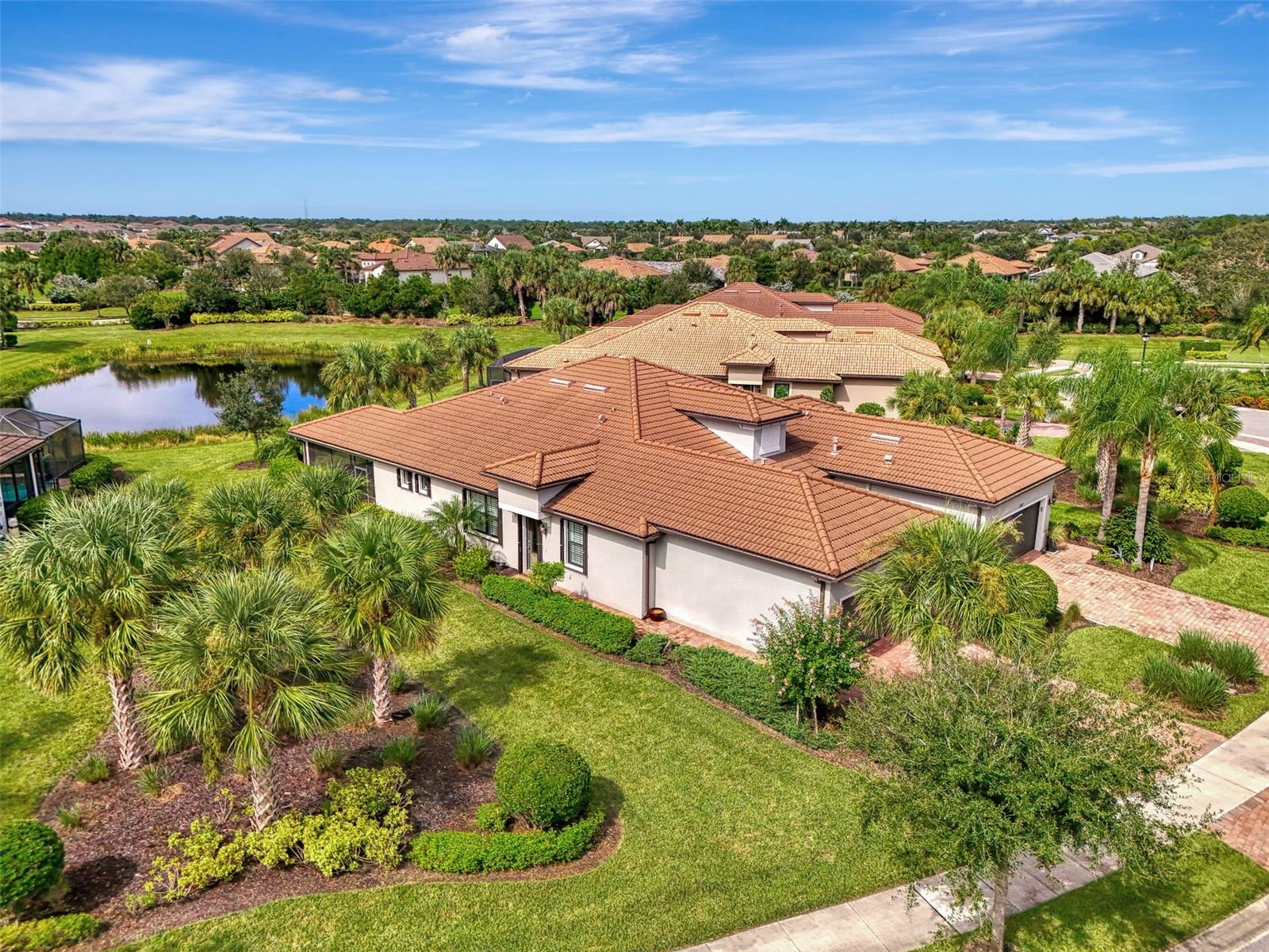 THE FLORIDA LIFESTYLE YOU DESERVE IN THE AMENITY-RICH COMMUNITY OF HAMMOCK PRESERVE! Casual elegance best describes this 2019 built Palmer Ranch 2 BEDROOM, 2 BATH, +DEN & 2 CAR-GARAGE VILLA in Hammock Preserve. Arguably, THE BEST VILLA LOT in the community with almost double the lot size of surrounding villas WITH SPARKING WATER VIEWS & LUSH GREEN SPACE.
The designer glass front door, transom windows in the living room and southeastern facing windows all contribute to the beautiful natural sunlight that fills the main living spaces of this home making it light, bright & airy. You’ll love the neutral color palette and open concept design incorporating the living room, dining room and kitchen spaces with 9’ ceilings and 8’ interior doors. You’ll especially love the 21” ceramic tile flooring throughout the whole home – in true Florida fashion with absolutely no carpet at all! The spacious kitchen has a breakfast bar, closet pantry and the stainless appliances include a French door refrigerator with pull out freezer below, dishwasher, sink, oven, and microwave. Timeless Shaker-style cabinetry with crown molding, quartz countertops and a beautiful tile backsplash complete the design. Three 8’ glass sliders leading out to the expansive covered lanai extends your living space to the outdoors where you can enjoy the gorgeous water views. A true split floor plan with the large primary bedroom with ensuite bathroom and walk-in closet located at the back of the home and the 2nd bedroom suite at the front of the home. A pocket door closes off the 2nd bedroom suite to provide your guests with plenty of privacy. The flex space currently being used as a den has double doors, built-in shelves and a desk space. Home features and seller improvements include PLANTATION SHUTTERS • BUILT-IN SHELVING WITH DESK IN THE DEN • PREMIUM OVERSIZED WATERFRONT LOT • EXTENDED COVERED 19’ X 14’ • SCREENED LANAI • QUIET DIRECT CURRENT CEILING FANS • AND ACCORDIAN-STYLE STORM SHUTTERS.
Hammock Preserve is one of Sarasota’s most desirable gated, maintenance-free communities, with resort-style amenities that include a community pool & spa, clubhouse, tennis & pickleball courts, bocce ball, two dog parks, a fitness center, fire pit, poolside community grills & more!
This villa is PRISTINE & MOVE-IN READY NOW! Be sure to ask about the FURNITURE PACKAGE offered under a separate agreement. Whether you’re looking for a sweet winter retreat or a year-round residence, this villa fits the bill! DON’T WAIT – SCHEDULE YOUR SHOWING TODAY!