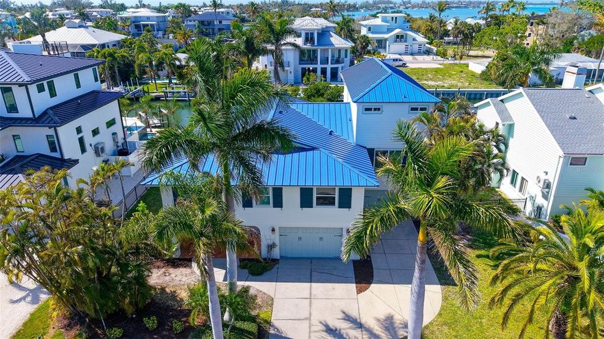 Boaters will love this spacious elevated home in a premier waterfront location on Longboat Key with dock, lift and by boat it is just four homes from the intercoastal, open bay waters and a short boat ride to the Gulf. Built for large gatherings, this home is beautifully designed with loads of gathering and entertaining spaces. The open plan home was thoughtfully designed with five bedrooms, four with en-suite baths. The kitchen features custom wood cabinets and granite countertops. Entertaining will be a breeze with two large gathering spaces, including a great room with dining area and adjacent bonus room that would be a wonderful media or game room. Ground level highlights include two bonus areas and a huge four-car garage. The composite dock has a 10,000-pound boat lift, water and electric. Recent updates include hurricane windows and doors (2025), metal roof (2025), pool equipment and pool heater (2025) and interior freshly painted. This location on Longboat Key can't be beat with community beach access just across the street, and a heated pool and boating in your own backyard. This is the ideal home to create wonderful island memories.