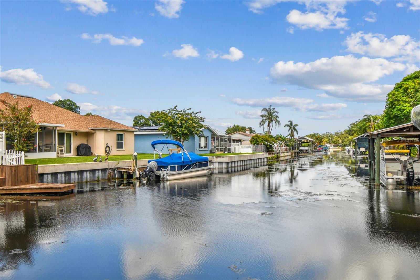 With stunning water views and unmatched outdoor access, this 3-bedroom, 2-bathroom home is a dream for anyone who enjoys waterfront living. The interior features a galley-style kitchen with granite countertops, wood cabinetry, stainless steel appliances, a separate dry bar area with a bar refrigerator, and a convenient passthrough. The open-concept living and dining spaces flow seamlessly into an additional rear room—perfect for taking in the breathtaking view year-round.
Step outside to your own personal retreat: a saltwater pool with LED lighting, powered by a self-adjusting heat pump/chiller (2023), and a 3” deck drain (2025) for easy maintenance. The newly added covered outdoor area (2025) is fully wired with electricity and includes a sitting space, hot tub with electrical, and built-in fan for warm days.
This property has experienced no flooding or storm damage. Proactive lake management includes lowering the water level and opening locks to Tampa Bay before major weather events, minimizing flood risk. The canal leads directly to Florida’s second-largest freshwater lake—Lake Tarpon. And if you’re into boating, the Gulf of Mexico is just 2.6 miles away.
Recent updates include new metal roof (2022), LED pool lighting (2022), Composite deck with lifetime warranty (2020), Water heater (2020), Electrical wiring for hot tub (2024). A full list of upgrades and features is available—there are simply too many to mention!
Enjoy optional access to the Lake Shore Estates private boat ramp—just 0.2 miles away—for $30/year. The community clubhouse is available for rental by members ($60 + $50 deposit), offering a full kitchen and indoor/outdoor lakefront space. Pet lovers will appreciate the neighborhood dog park, and golf cart owners will feel right at home with holiday parades and regular rides around the neighborhood. Come experience the Lake Shore lifestyle—where every day feels like a getaway.