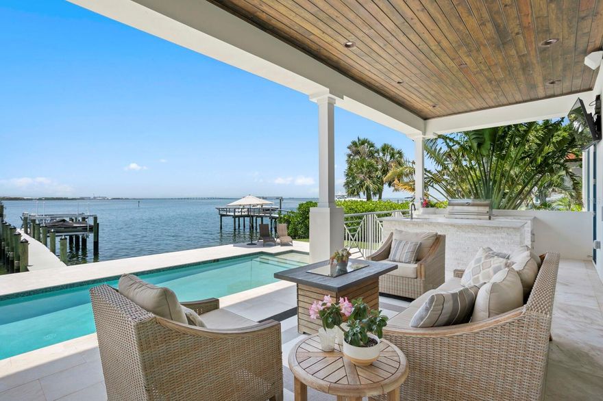 Introducing an exquisite blend of sophisticated coastal living and wide-open bay views in this 2020-built Sunset Park waterfront estate, thoughtfully enhanced with over half a million dollars in curated upgrades. From the moment you step through the stylish double doors, you're drawn in by breathtaking open-water views, framed by a warm, neutral palette and rich hardwood floors, providing an elegant finishing touch. Built to the highest standards with concrete block construction and impact-rated windows and doors, every detail of this home has been thoughtfully curated for style, function, and resilience. The first level offers a seamless layout for entertaining, featuring a formal living room with fireplace, a formal dining room, and an inviting family room anchored by a media feature wall. The chef’s kitchen is designed for both intimate and large-scale gatherings, boasting honed marble countertops, a generous center island, Wolf and Sub-Zero appliances, a large butler’s pantry, and wine refrigeration. An ensuite guest suite and a stylish powder bath complete the first floor.
Upstairs, enjoy a spacious loft and five ensuite bedrooms (or optional bonus room), including a luxurious primary suite offering panoramic bay views, a sitting area, an oversized custom closet/dressing room, and a private terrace overlooking the water. The marble-clad primary bath is a sanctuary featuring a soaking tub, a glass-enclosed shower, and a morning bar with a beverage station. Retracting glass doors lead to a spacious covered waterfront terrace with a fully equipped outdoor kitchen—well-suited for seamless indoor-outdoor entertaining. 
The backyard has been extensively upgraded with a pool and spa, as well as a reimagined patio surrounded by professionally designed landscaping and ambient uplighting. Enjoy 90 feet of deep-water frontage with a new dock and dual boat/jet-ski lifts (16,000 and 10,000 lbs), designed for boating and waterfront recreation. A Control4 smart-home automation and full-home surround-sound system elevate comfort and connectivity throughout. Additional thoughtful upgrades include automated window treatments, custom blinds, updated lighting and ceiling fans, garage cabinetry, a water-softener system, and a 3+-car garage with room for lifts, completing the offering. This elevated home is designed for enhanced protection and performance in all seasons. All just minutes from highly regarded schools, Downtown Tampa, International Plaza, Tampa International Airport, and the Gulf Coast’s renowned beaches—a showcase of refined waterfront living. May be purchased furnished at additional cost.