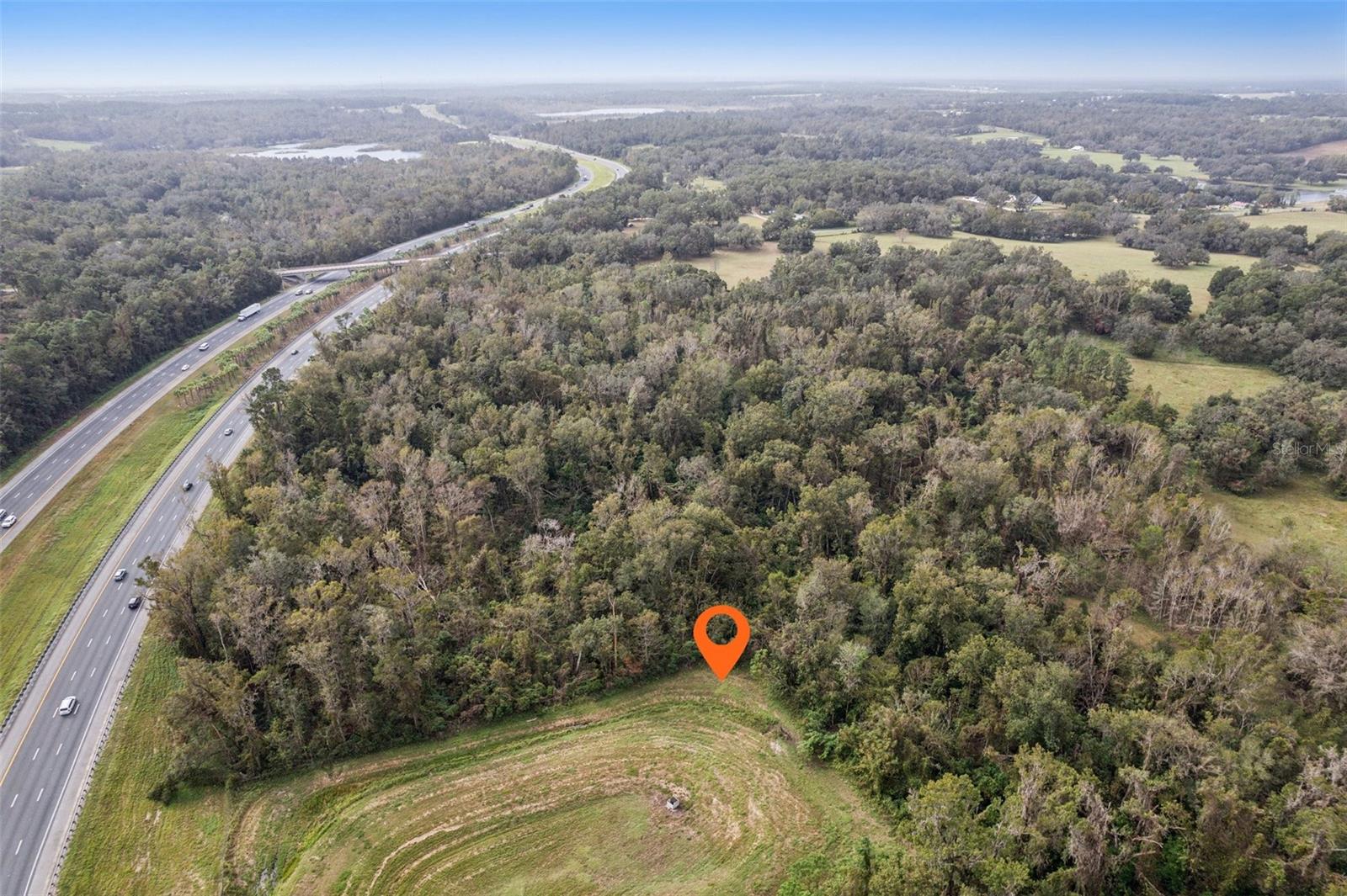 A prime 8.10-acre vacant lot in Spring Lake, Florida, near Brooksville, presents a unique opportunity for mixed-use development with significant frontage on Interstate 75, ideal for a green space town concept; the property features substantial wooded land, an underground spring stream, and is currently zoned agricultural, requiring zoning changes through Hernando County Building, Zoning, and Planning Divisions for any development plans; easily accessible via street address 28063 for street view reference.