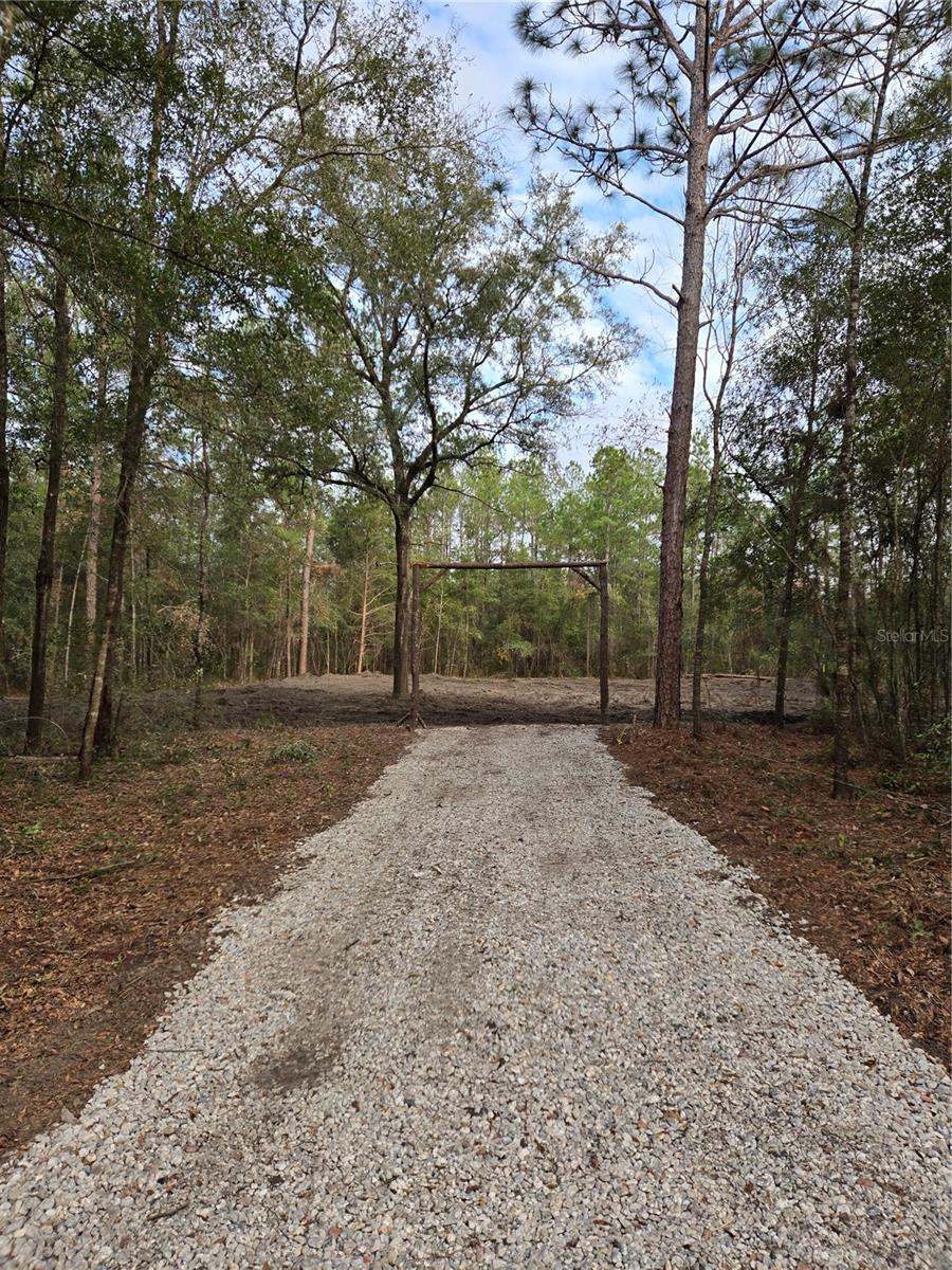 Discover the perfect blend of country living and modern convenience with this 1-acre parcel (210x210 ft) in Williston, FL. Zoned Residential Agricultural, this property offers endless opportunities—whether you’re looking to build your dream home, establish a small homestead, or invest for the future.
A 105x105 ft cleared, de-stumped, and graded area is ready for immediate construction. The property also features a gravel driveway with charming ranch-style arches, plus an electric pole already in place, saving you time and expense in the building process. Accessible year-round, this is the only lot in the area that’s cleared, graded, and equipped with a driveway—a rare find! Also, there are no minimum square footage requirements to build. Ideal for tiny homes, manufactured homes, or even a site built single family home. The only thing the county asks is that you follow Florida Building Code.
Enjoy privacy and space while staying close to conveniences: schools, shopping, and dining are just minutes away. Major hubs like Ocala and Gainesville are a short drive, with easy access to nearby highways and the interstate.
As a bonus, the seller is offering a $1,000 credit toward clearing seasonal weeds upon purchase—making this land even more turn-key.
Lot 9, an adjacent 1-acre lot, is also available.