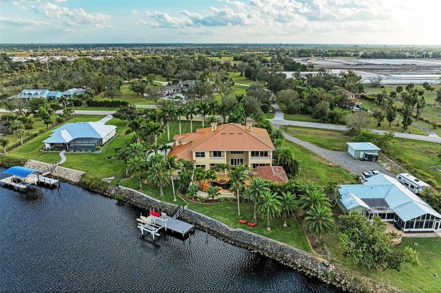 This Unique, Mediterranean Inspired Private Estate on nearly 1 Acre Shell Creek is the idyllic home to live, work, play, & entertain, with 5 bedrooms & 3.5 bathrooms in the main home & a separate GUEST HOUSE with an additional bedroom, bathroom, & kitchenette, all on the water with a resort style pool/spa with custom stone work & waterfalls, all overlooking Shell Creek with great privacy & a large dock with 10,000lb lift! A commercial grade generator & Impact Glass/Shutters, coupled with a NEW CUSTOM STANDING SEAM METAL ROOF on high ground all mean that this is the shelter you desire.  Opulent details abound on the exterior as you enter through the gates down the large circular driveway with stately landscaping.  Through the custom front doors be captivated by the 26' tall grand foyer open to the spacious great room with gas fireplace, voluminous coffered ceilings and a wall of windows overlooking the pool.  Throughout the home find imported Italian marble flooring in the main living areas, hand rubbed faux paint treatments on the walls & ceilings, a custom radial staircase with custom iron railings leading to the second floor, granite counters, custom trim, upgraded appliances, & many other luxurious features listed in detail on the attached FEATURES SHEET! On the main floor, find a formal dining room off to one side near the kitchen with Viking & Fisher & Paykel appliances which is open to the dinette & connected to both the great room & the entertaining room.  The entertainment room overlooks the water & has room for everyone with a large bar with glass fronted shelving, seating for guests, & conveniently located additional dishwasher, ice maker, & a beverage center. Also on this side, find a powder room with hammered copper sink, the downstairs laundry room, & connection to the pristine 3 car garage with Tesla charging station. On the opposite side of the great room on the main level, find a media/theater room (which could also double as a bedroom with closet), & farther down the hall, the primary bedroom #1 awaits with sliding door access to the lanai, dual walk-in closets, & an en suite bathroom with slate floors, a jetted tub & multi-head walk in shower, along with dual vanities & a private water closet.  Upstairs, find a matching primary suite, with similar finishes & identical in size with a private balcony! Also upstairs off the right side of the home is a guest bathroom with separate Roman shower & tub with dual vanities & makeup desk, serving 2 additional guest bedrooms that overlook the waterway & preserve beyond. Farther down the hall find the upstairs laundry with cabinetry & sink, the custom library/office with cherry wood shelving/library ladder, & maple flooring, & at the end of the hallway, a final guest suite awaits with window seat, great closet storage, & a full en-suite bathroom.  Back downstairs & outside on the terrace, enjoy multi-level entertaining around your resort style pool/spa with beautiful waterfall & lighting features.  To the left of this space is a spiral staircase leading to the upstairs balcony of the 2nd level primary suite & a separate connection to the guest house/cabana, which has it's own kitchenette, bedroom & bathroom with pool access, & great storage, also with Italian Marble flooring throughout.  Beyond the pool area, choose your path to the water, where the dock/lift/seawall are in pristine condition This home has it all, and is priced to sell, so schedule your showing today!