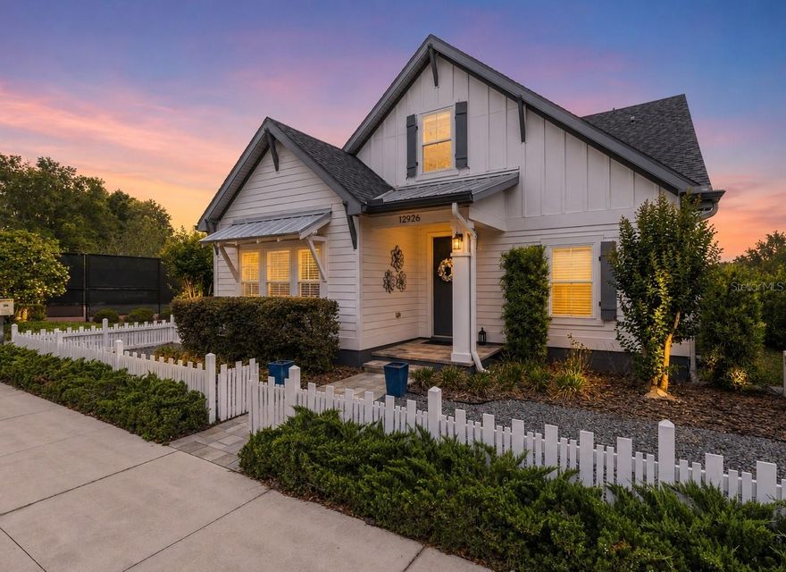 Built in 2020 and thoughtfully upgraded, this Town of Tioga home delivers the rare combination buyers want most: newer construction, low-maintenance outdoor living, flexible interior space, and walkable neighborhood amenities. A white picket fence frames the front, app-controlled permanent holiday lighting sets the tone for each season, and the rear-entry garage opens to the shared green space that Town of Tioga is famous for. In the side yard, a covered paver lanai, an upgraded deck, and two additional outdoor spaces extend the living space outdoors for morning coffee, afternoon grilling, or weekend entertaining. Inside, natural light moves through the open living area, highlighting tray ceilings, crown molding, and clean sightlines from the kitchen to the living and dining spaces. The kitchen anchors the home with quartz countertops, a modern tile backsplash, stainless appliances, and a premium induction cooktop and ventilation hood. The main-level primary suite feels like a true retreat, with a soaking tub, oversized dual-head shower, custom Elfa closet system, integrated laundry, and a towel warmer - small luxuries that elevate the everyday routine. A main level bedroom with barn doors and attached full bath can serve as a fourth bedroom, guest space, office or studio. Upstairs, two additional bedrooms, a full bath, a generous bonus room, and a second laundry area create a highly functional space for kids, guests, fitness, or work-from home needs. Town of Tioga adds the lifestyle amenities that buyers come here for: green spaces, nature trails, community garden, resort-style pool, courts, shops, restaurants, and year-round community events. With newer construction, thoughtful upgrades, flexible living spaces, and one of Gainesville’s most walkable village-style settings, this home is designed for easy everyday living and effortless entertaining.