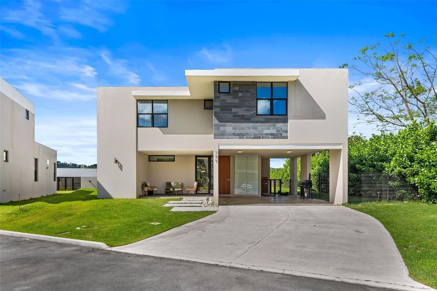 Welcome to River Terrace — a gated residential community in Gurabo, Puerto Rico, with 24/7 security, Club House, and community pool. This two-story, three-bedroom, two-and-a-half-bath residence was built new andit offers roughly 1,950 sq ft of well-designed living space on a lot of approximately 618 m².

The curb appeal sets the tone immediately: a modern flat-roof facade with slate stone accents, a covered carport, and a manicured front yard welcome you home. Inside, the ground level opens into a bright, open-concept living and dining area with direct access to a rear yard — an ideal extension of the social space. The chef's kitchen anchors the floor plan with a large center island topped in quartz, an induction cooktop with ceiling-mounted glass range hood, high-gloss upper cabinetry, wood-tone lower cabinets, and a complete suite of stainless steel appliances: French door refrigerator, double wall oven, built-in microwave, and wine cooler. A powder room completes the first level.

The upper level hosts three bedrooms and two full baths. The primary suite features an inverter mini-split air conditioning system, a walk-in closet with built-in shelving, and a private en-suite bath with double vessel sinks on a floating vanity, bidet, and full-wall illuminated mirror. 

Two additional bedrooms — one with a custom botanical accent wall and built-in closet organizers — share a well-appointed full bath and natural light and views of the community's green areas.

Energy resilience is a defining feature: 22 solar panels and two Tesla Powerwall batteries deliver reliable, grid-independent power — a practical and measurable advantage in Puerto Rico's current energy landscape.

River Terrace provides 24/7 access-controlled entry, professional security, Club House, community pool, and playground — all HOA-maintained. The owner covers HOA fees on the tenant's behalf. Contact listing agent to schedule a showing.