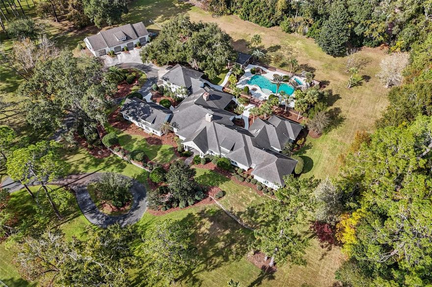 Location and lifestyle! This exquisite property offers the best of both! Situated on 4.5 landscaped acres of in-town living in University Acres, just north of HCA North Florida Hospital and only minutes to the University of Florida, this sprawling estate was built in 2003 by luxury custom home builder, Mark Warring, as his personal residence. Boasting 7510sf of heated/cooled space, there are 6 bedrooms, 2 offices, a library, rec room, home gym with wet bar, designated gift wrap room, 5 full bathrooms, 2 half bathrooms, a large stop-n-drop mud room with built-ins, and so much more! The chef's kitchen was recently renovated and features coffered ceilings, solid wood cabinetry, quartz counters, double islands, convection wall oven, 6-burner gas cooktop, breakfast bar, walk-in pantry, additional beverage refrigerator, and a built-in desk area. The great room features vaulted & wood-beamed ceilings, a soaring stone fireplace, a designated dining area, and incredible views of the backyard. The primary bedroom features coffered ceilings, two walk-in closets, a large ensuite bathroom, a sauna, and an ensuite office with a brick accent wall and built-in bookshelves. Accessed via a private entrance in the west courtyard, the second office has gorgeous vaulted wood ceilings, brick accent walls, built-in cabinetry, and a half bathroom. Above the attached garage is an apartment with a kitchenette, living room, bedroom, and full bathroom. Outside you will be wowed by the commercial sized swimming pool, 15-person hot tub, waterfall, cabana, summer kitchen, screened porch with fireplace and a basketball court. Need a place to store your boat or RV? Check! The detached 4-car garage has a RV garage door along the back of the building and features a full bathroom, as well as a large workshop. The Sellers are in the process of refurbishing the property and interior photos will be added in February 2025.