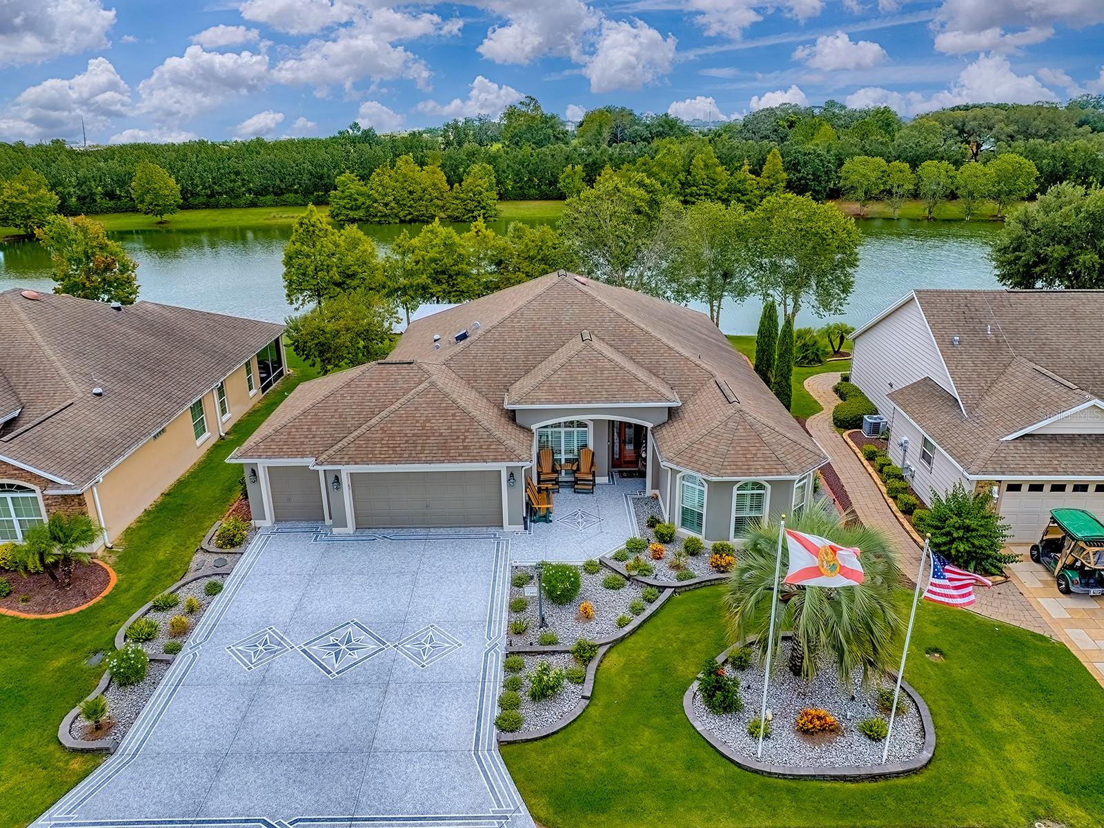 BREATHTAKING WATER VIEW on this EXPANDED 3BD/2BA GARDENIA Designer with 2 car+ GOLF CART GARAGE located in the VILLAGE of ST. JAMES! This LOVELY home offers great CURB APPEAL with stacked stone curbing, EXPANDED painted drive and walkway, custom front PATIO with a STUNNING LEADED GLASS front door with sidelite and transom. Once inside you’ll find DIAGONAL TILE FLOORING throughout the foyer, kitchen, and walkway which transitions into LOVELY HARDWOOD flooring in the living and dining room. The spacious kitchen has attractive CHERRY cabinetry, GRANITE countertops, mosaic tiled backsplash, NEWER STAINLESS appliances with a smooth top electric COOKTOP, bottom freezer refrigerator, and 2 WALL OVENS, an ISLAND with extra storage, a breakfast bar with pendant lighting, and an EAT-IN CASUAL dining nook. A custom large PANTRY was added around the corner for plenty of storage space. CROWN MOLDING and PLANTATION SHUTTERS are just a few of the upgrades that you will find throughout this BEAUTIFUL home. Wood cornices adorn the STACKED BACK sliding glass doors that open to the beautifully TILED 13’x30’ insulated GLASS ENCLOSED LANAI. This AMAZING additional 381 sf of living space offers a SPECTACULAR VIEW of one of the best WATER VIEWS in The Villages. A great place to relax, dine, or entertain with the mini-split providing comfort all year round. Step outside to the pavered patio where you have an abundance of outdoor living space with another concrete patio with a HOT TUB covered with an attractive PERGOLA. Back inside through a pocket door off the foyer are your 2 expanded guest rooms and guest bath as this side of the home was stretched 3 ft. The front guest room has lovely HARDWOOD flooring, 3 large windows from floor to ceiling for lots of natural light, and a tray ceiling with crown trim but does not have a closet. A great room for an office/den should you prefer. The other guest room has vaulted ceilings, the same lovely flooring, and a double door closet. The guest bath has granite countertops, and a tub/shower. The spacious primary bedroom has carpet with a crown trimmed tray ceiling, a wall mounted TV that does convey with the home, custom doors added for easy access to the hot tub, and an EN-SUITE BATH! The hallway to the bath has 2 large WALK-IN CLOSETS; the primary bath has a linen closet, dual vanities, granite countertops, ROMAN SHOWER, and a separate toilet room. The 2 car+ golf cart garage has a workshop, pull down attic stairs with carpeted flooring in the attic and a solar fan. A storage room was created in the garage but should you have 2 golf carts and need the space, it’s an easy fix. Other features include a 2024 WALTER FILTRATION SYSTEM, gutters around the entire home, beautiful custom landscaping around the entire home, and even a PEACH tree. This is a prime location between Lake Sumter Landing and Brownwood. Surrounded by golf courses and plenty of recreation centers! COME SEE ALL THIS BEAUTIFUL HOME AND MAGNIFICENT VIEW HAS TO OFFER!