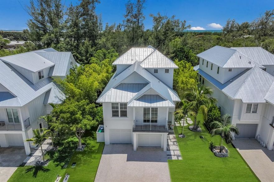 Enjoy the quintessential island life in this stunning custom home in Longboat's favorite north end neighborhood. Mason-Martin custom build with no detail spared.  Designer furnishings included. This home has an endless list of custom features, easy beach access, and convenient neighborhood boat ramp with kayak launch. You are only steps to your beautiful Gulf beach. Drop your kayak or boat at the neighborhood launch, stroll or take your golf-cart to neighborhood restaurants, shops, and more. You will take comfort in knowing that this home was built to the highest of standards: concrete masonry construction, hurricane impact windows and doors, 50-year metal roof, a private elevator, a 10-year builder's warranty, and much more. The front of the home greets with its coastal craftsman architecture. Inside, the open floor plan is welcoming and you will be impressed by the eight-foot paneled doors, volume ceilings, detailed carpentry, window treatments, and plank wood flooring. The outside seamlessly flows as you will find a multitude of spaces to relax, entertain, and enjoy the casual island life. The  floor plan features a large chef-inspired kitchen that boasts Wolf & Sub-Zero appliances, gas cooking, custom cabinetry, quartz tops, and a large center island. The great room opens to the dining area and a large open lanai. Beyond the great room you'll find two private guest bedrooms, both en suite with full baths. The upper level master features two walk-in closets, beautifully appointed bath with tub, walk-in shower, and a private lanai that overlooks the pool, spa, and outdoor entertaining areas. There is even a bonus room with flat screen television, wet-bar, comfy seating, and half bath. The double-car garage has plenty of room for storage and a golf cart. Outside you'll find a refreshing saltwater pool, heated spa, covered  and open lanai areas, grill station, travertine decking, and an outdoor shower. The home is beautifully landscaped with tropicals and palms, though you will also be pleased to know the yard itself is a zero-maintenance, pet-friendly synthetic turf. The home comes completely turnkey-furnished - from the designer-inspired furniture package all the way down to linens, towels, dish and bar ware, artwork, and smart televisions. Live inspired. Live the island life.