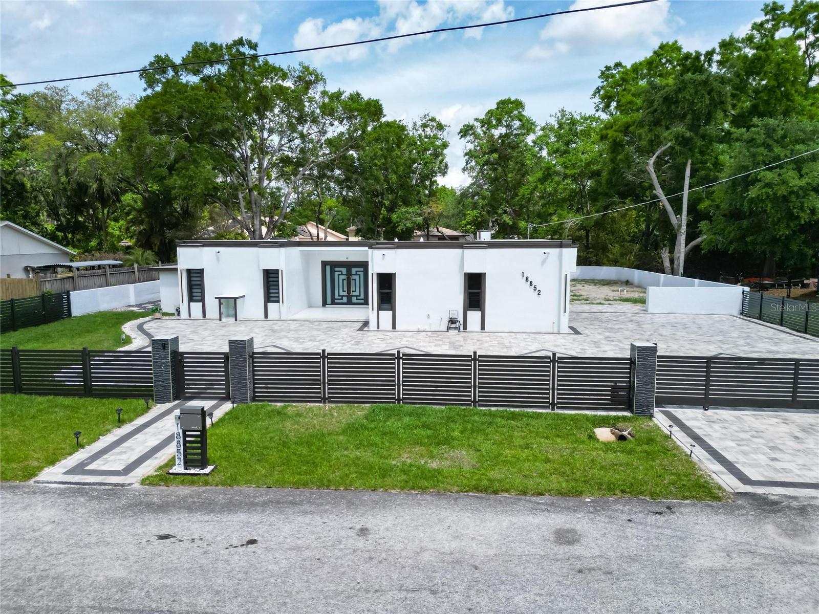Perfect for relocation, investment, Airbnb, or your dream vacation home! Welcome to your dream property in Lutz—where modern comfort meets elegant design in a peaceful natural setting. This stunning fully remodeled 4-bedroom, 2-bathroom residence blends sophistication, functionality, and convenience. Just 15 minutes from downtown Tampa, it’s a rare opportunity for savvy buyers or investors looking for a move-in-ready gem. Set on a private lot with breathtaking lake views, the property includes a charming bridge that crosses over the water, leading to an additional backyard space surrounded by nature. The peaceful vibe is complemented by its proximity to Tampa’s top shopping malls, featuring high-end brands and dining options just minutes away. The front of the home offers a two-car garage, a fully paved driveway, and a premium security fence with a coded entry gate. Inside, you’ll find luxury porcelain tile throughout, a designer kitchen with modern cabinetry and Panda quartz countertops, and spa-inspired bathrooms with sensor-activated faucets and sleek finishes. Each bedroom features custom walk-in closets for optimal style and organization. This home also includes a brand-new well with filtered water, eliminating the need for city water services. The outdoor space is made for enjoyment and entertaining, featuring a fully paved, screened-in lanai with a complete summer kitchen—outfitted with weather-resistant aluminum cabinets and a stone countertop. A beautiful pergola in the rear adds charm and shade. Plus, the property is already prepped for a future pool, with a 220V subpanel and plumbing in place—giving you a head start on your dream oasis. Additional highlights include hurricane-impact doors and windows, a brand-new roof (2024), Flood Zone X, no CDD, and no HOA—giving you the freedom and peace of mind you deserve. Don’t miss this rare opportunity to own a standout home in one of Lutz’s most desirable areas. Schedule your private showing today!