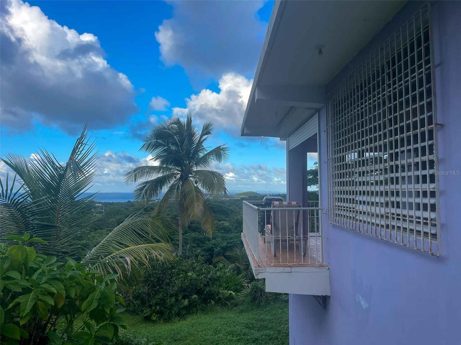 Introducing "Casa Verde," an enchanting 2-bedroom concrete structure nestled within the lush landscapes of Vieques, Puerto Rico, aptly named after the verdant greenery embracing the house and its surroundings. This two-story home offers an exceptional opportunity, featuring stairs leading to an unfinished roof deck that holds the promise of becoming a breathtaking third-floor space. The first floor boasts a storage room and convenient parking while being embraced by a meticulously landscaped garden sprawled across half an acre, creating an oasis of tranquility. Surrounded by pristine pasturelands, this property offers awe-inspiring vistas of the Caribbean Sea, mainland Puerto Rico, Vieques’ sister-island of Culebra, Isabel Segunda, and the north shore of Vieques.
From the open balcony living room to the potential third-floor deck, immerse yourself in captivating sunrises, sunsets, and the rhythmic dance of ferries voyaging to and from Ceiba. Embracing an open-concept design, the interconnected kitchen, dining room, and living room invite both entertainment and the soothing trade winds from the east. The primary bedroom indulges in space for a king bed and furnishings, complemented by an ensuite full bath featuring a glass block shower. Step outside to a back patio with an outdoor shower and bathtub, inviting you to unwind amidst the harmonious blend of nature and ocean vistas.
Convenience meets elegance with a laundry closet within the primary bedroom, while an adjacent office area off the main entrance and dining room offers versatility, potentially serving as an additional bedroom. A second full bathroom with shower and ample closet space caters perfectly to guests or occupants of the second bedroom. The second bedroom, delineated from the living room, includes a spacious closet, allowing for potential privacy enhancements.
The kitchen, adorned with a concrete countertop, gas stove, and decorative tiles, is illuminated by a wall of windows that infuse the main floor with natural light. A kitchen island provides versatility for baking, crafts, or casual dining. The property is fenced and adorned with mature plants, with palm trees framing the mesmerizing views from the house. Situated atop the hills above Monte Santo, this haven resides at the road's end, ensuring tranquility with minimal street traffic, fostering an oasis of peace.
Boasting tall ceilings and abundant windows facilitating gentle light and refreshing breezes, Casa Verde embodies comfort, elegance, and the quintessential Vieques lifestyle. Paraiso Realty cordially invites you to experience this captivating property, where each corner narrates a tale of serenity and unparalleled vistas, promising an idyllic retreat in the heart of Vieques, Puerto Rico.