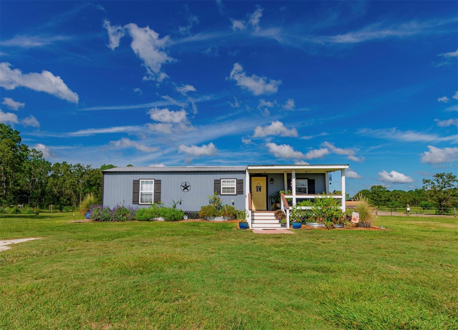 Escape to your own private oasis with this fully fenced 10-acre horse farm, perfectly set against 318 acres of neighboring farmland. Built in 2022, this unique 1-bedroom, 1-bath home offers 736 sq. ft. of thoughtfully designed living space, blending modern touches with rustic charm. Inside you’ll a find tongue-and-groove ceiling, abundant natural light and durable LVP flooring throughout. The kitchen is equipped with ample cabinetry, generous counter space, a gas stove and a pantry. The spacious bedroom is conveniently located near the bathroom, which features a charming clawfoot tub with shower. Front and back porches provide peaceful views of the property, while an above-ground pool offers a refreshing retreat on warm summer days. The grounds are just as impressive as the home. A beautifully landscaped garden features raised flower beds, graceful magnolia trees and a stunning row of plantings designed to attract birds and butterflies. Designed for equestrian living, the property includes 3 run-in sheds with stalls (totaling 9), 3 separate pastures with room to add another one, a chicken coop and a 10x20 finished tack/feed room that is partially insulated and pre-wired. Additional improvements include a 21x27 metal garage with electric, concrete floor and washer/dryer hook-up, a covered 20x20 overhang with concrete slab and a 14x40 pole barn for farm equipment and storage. A 50x30 RV site with hookups offers the perfect setup for visitors, traveling equestrians, or additional living space.
Recent updates include a new drainfield (2021), well pump and tank (2021), appliances (2022), and washer (2025). The property also features 4 separate well zones to support farm needs. Enjoy a prime location just 30-miles to the World Equestrian Center in Ocala, 19-miles to HITS , 11-miles to Black Prong and only 9.5-miles to Goethe State Forest, home to hundreds of acres of scenic riding trails. Shopping, dining and everyday conveniences are also within easy reach. This property offers the perfect blend of country living, equestrian functionality and natural beauty—ready for its next owner!
