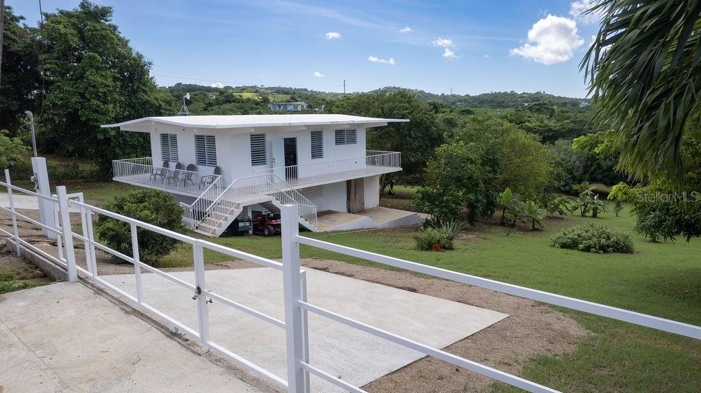 Casa Shaman is a turn-key newly remodeled two-story home is situated in the quiet and serene neighborhood of Bastimento. The surrounding grounds are a nature lovers dream with with numerous fruit trees and local spices (Corazon, Mango, jobo, achiote, oregano brujo, cereza, and many more). With almost one acre of land, the property also provides ample space for outdoor living and future expansion, the addition of a pool, garage, and/or guest house.
The upper level of the structure is the heart of the home, with an open-concept living area with kitchen, dining, and living spaces seamlessly flowing into each other. The wraparound balcony offers sweeping views of the lush surroundings. This level also includes two spacious bedrooms and one full bath.
The first level has an large unfinished versatile studio that includes a full bathroom and kitchenette. The space can be finished as a one bed, one bath loft for guests or as an income producing rental. The generous space is large enough to keep a storage area, ideal for all your gear or as a potential workspace.
With a gated, paved entry, this home offers peaceful, quiet living at just a short distance of all your needs. The bustling town center is a quick 5-minute drive away, offering easy access to shops, restaurants, and amenities, and Bastimento Beach is only a 15 minute walk from the property.