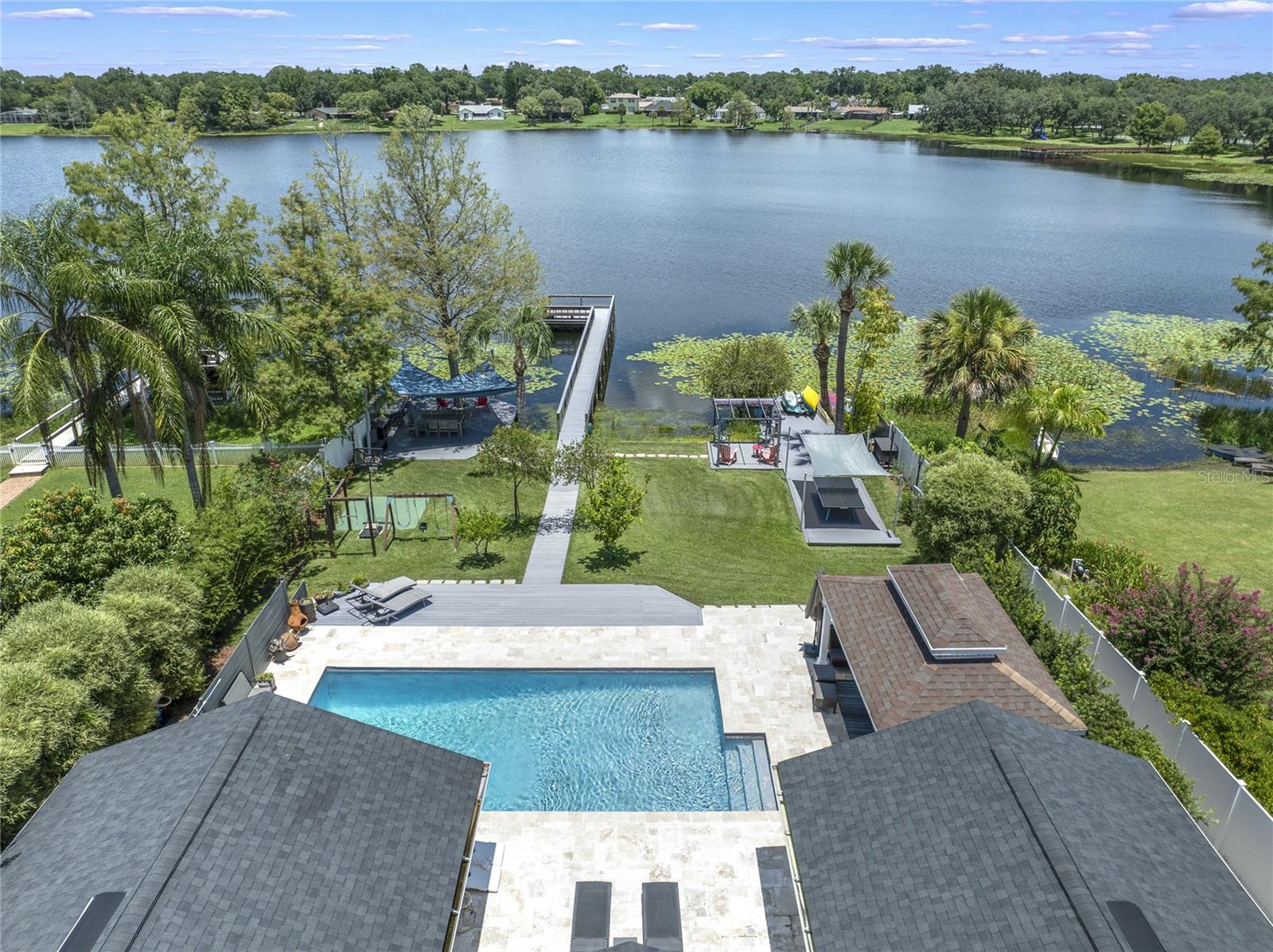 Stunning Lakefront Oasis in the Heart of Dr. Phillips
Welcome to your dream home on the tranquil shores of Lake Sloat, perfectly situated in the heart of Dr. Phillips, Orlando. This immaculate 6-bedroom, 4.5-bathroom estate spans over half an acre of private lakefront and offers an unmatched blend of luxury, functionality, and outdoor living.
Enjoy direct lake access with multiple composite decks including a dining deck with UV-protective sail, a boat and kayak storage area, and a dock with platform seating, all built with treated support beams for lasting durability. A gazebo with ceiling fan and lighting sits beside the oversized 35’ x 16’ pool, surrounded by travertine decking and framed by a privacy wall with premium aluminum fencing. There's also a deck with aluminum structure near the lake, sail shade over a ping pong area, and a cement basketball pad for additional recreation.
The expansive yard is thoughtfully designed with low-voltage landscape lighting, cement walkways on both sides of the home, a jungle gym and swing set, and a dedicated vinyl-fenced trash area. The front driveway, porch, and side entrance are all upgraded with pavers, including a new widened cement driveway ramp for smooth street access.
Inside, the home boasts all-new flooring in bedrooms, hallways, and the office, refurbished laundry room with new cabinets and flooring, and remote-control blinds on most windows. The layout includes a double primary suite configuration, ideal for in-laws or guests, and a private office with half bath.
Major upgrades throughout the home include:
All windows replaced with double-pane glass
New roof
Replaced both HVAC systems
Whole-house repiping
New external gas hot water heater
New electrical panel
New pool pump motor, saltwater system, and heat pump
Gutters on all sides
Motion-sensor security lighting on each side of the home
Protective epoxy garage flooring with ceiling-mounted storage
Spacious storage shed
For outdoor entertaining, the courtyard includes a decorative fountain and a fully equipped summer kitchen with grill, sink, fridge, storage, and stone counters—perfect for lakeside gatherings.
This one-of-a-kind property offers luxurious upgrades, extensive outdoor living, and rare lakefront tranquility in a premier Orlando location. Schedule your private showing today—homes like this are rarely available.
