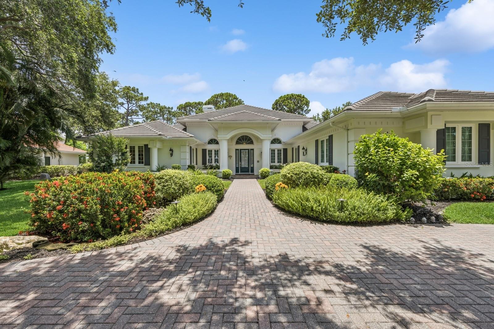 Discover refined living in this extraordinary Georgian-style estate located in the prestigious gated community of TPC Prestancia. Nestled on a rare Southern exposure lot, this residence offers breathtaking lake and golf course views, lush privacy, and timeless architectural charm within one of Sarasota’s most desirable golf communities. Set well back from the street on a gracious circular driveway, this one-story home features a stately front façade with a remarkable symmetry in the architecture, tall windows, mature landscaping, and elegant curb appeal.
Inside, you’ll find a thoughtfully designed floor plan with 4 bedrooms, including two ensuite guest suites, a private office, formal living room, spacious family room, catering kitchen and laundry room. At the heart of the home is a gourmet chef’s kitchen, open towards the family room and outdoors, fully outfitted with Viking appliances, Subzero refrigerator, plate warmer, wine cooler and high-end finishes like very rich green granite countertops. For effortless entertainment, the residence offers a separate catering kitchen with a second set of appliances. The formal dining room comfortably seats 12 guests, enhanced by custom triple crown molding and refined architectural detail. Entertain in style with two custom wet bars, including a unique Moroccan-inspired bar with a striking blue ceiling—a true conversation piece just off the family room.
The owner’s suite will be your retreat with serene views on the backyard and golf course, a direct access to the pool. Spacious primary bathroom and two California walk-in closets bringing luxury and practicality together.
Same comfort in the three guest bedrooms offering high ceilings, ample storage and relaxing views.
Step outside into a private tropical oasis: a resort-style pool and spa, expansive lanai, and outdoor kitchen are framed by lush backyard. The pool cage was rescreened in 2023, and a charming gated patio with wrought-iron gates offers a secluded nook for peaceful relaxation. This residence is loaded with high-value upgrades and mechanical peace of mind: -Concrete tile roof (2013),Hurricane impact-rated windows (2014), Generator (2018), new water heater (2025), 3-car garage with storage and ample parking space. TPC Prestancia is a premier, gated golf community set on 565 acres of mature landscaping. Recognized as an Audubon Cooperative Sanctuary, the neighborhood is home to vibrant wildlife and peaceful walking paths. Golf membership is optional, with multiple plans available and no waiting list—offering flexibility for both golf enthusiasts and those seeking a serene, upscale environment.
Ideally located in central Sarasota, this Estate is just minutes away from Siesta Key and other Gulf beaches, short drive to downtown Sarasota and Venice and close to sports club, tennis, pickleball courts, YMCA, fine dining, shopping. This exceptional estate blends classic character, modern luxury, and an unbeatable location, making it a true gem in one of Sarasota’s most sought-after golf communities.
Make your appointment today for your private showing!