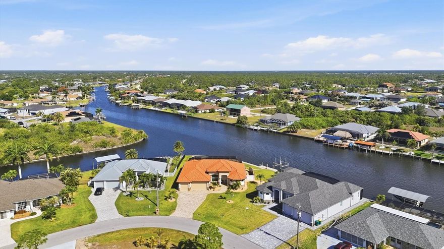 Located on a premium waterfront lot in South Gulf Cove, this meticulously maintained home is packed with upgrades and desirable features including impact windows and doors, granite countertops throughout, a heated pool, frameless lanai screen (2023), whole-house generator, 500-gallon propane tank, new roof (2023), water filtration system, a mist away system, hardwired security cameras, irrigation system (reclaim water), gutters, and a waterfront fire pit to name just a few. This tip lot (17,068 SqFt) offers panoramic water views of intersecting canals integrated throughout the interior and exterior living spaces. Enjoy stunning sunsets overlooking the widest section of the Zephyr waterway with 163 feet of seawall waterfront. Bring your boat, or plan for a future purchase, with your private dock featuring a 10,000-pound lift plus electric and water already in place. As you arrive at this waterfront oasis, you’ll immediately notice the curb appeal from the wide paver driveway, stonework accents, front porch, and decorative glass double-door entry. Once inside, your attention is instantly drawn to the expansive water views and your outdoor sanctuary visible through multiple sliding glass doors. The zero-corner pocket slider creates a seamless extension into the expansive screened lanai. Throughout the home you’ll find tile flooring, high ceilings, crown molding, recessed lighting, and rounded corners. The living room features a backlit entertainment wall with an electric fireplace, plus a double tray ceiling at 14’2”. Off the living room is the office/den with French doors. The kitchen open to the main living and dining areas features an abundant of soft-close wood cabinets with pullouts, two-tone granite countertops, dark stainless appliances, pendant lighting, backsplash, built-in pantry, and an additional 10-foot coffee bar opposite the oversized island. The primary and guest bedrooms are on opposite sides of the home providing ample space and privacy for all. The primary suite offers a double tray ceiling, lanai access, two walk-in closets with built-ins, additional storage, freestanding soaking tub, dual sinks, oversize walk-in shower, and of course water views. A pocket door closes off the guest quarters, which includes two bedrooms, one with lanai access, and a bathroom that doubles as a pool bath. The laundry room provides extra storage and a sink. The three-car garage accommodates extended-cab vehicles and features an epoxy floor, two side door entrances, a separate storage room, with both the garage and covered lanai having antic insulation. The spacious paver outdoor living area offers both covered and sun-exposed spaces within the screened lanai, creating the perfect setting to enjoy the Florida lifestyle. Whether you’re dining al fresco, entertaining family and friends, watching the game, lounging poolside, or enjoying your morning coffee while watching the wildlife and boaters, this home was truly designed for waterfront living. Step outside the lanai to play cornhole, throw the ball around, relax by the fire pit at the water’s edge or cruise around the waterways while taking in the sunset. An electric hurricane screen on the covered lanai provides added storage protection while out of town. Head out to the beach to change your scenery, visit one of the many local waterfront restaurants, or stop by Publix to pick up supplies, all of which are a short drive away from your Florida waterfront retreat. No CDD or required HOA fee.