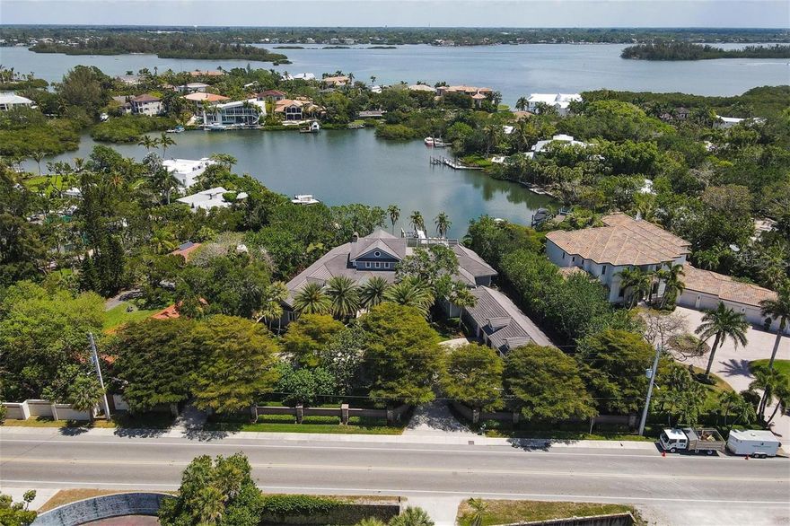 This home could be the main feature in Coastal Living magazine.  It truly is an amazing waterfront estate complete with a 12,000 pound boat lift, a floating dock, deep water on Cocoanut Bayou, a gated beach access and pilings for a large boat.  A true gated estate on a parcel of land that is over 3/4 acre. This custom built and designed residence is almost 4900 square feet of living space all on one floor. Its front porch has a beautiful garden view and is the ultimate viewing station for the mote that is complete with Koi fish.  Its back lanai features a covered outdoor living space that is 96x43.  There is a heated saltwater pool, an outdoor kitchen, a pool bath and screened sun terrace.   The outdoor space is great for entertaining and is accessible from all all main living areas inside.  A true 4 bedroom, 4 bath home with 3 half baths.  Upgrades include the kitchen with custom wood cabinets, concrete and quartz counters, a beverage center including an ice maker, water chiller, sparkling water, refrigerator drawers, and Miele espresso machine. A gourmet kitchen complete with hidden walk-in pantry, Subzero refrigerator and freezer, wine refrigeration, Viking gas range, Miele microwave, 2 dishwashers and more. The master bedroom includes an en-suite sitting room, a breakfast nook with built-in refrigeration and custom closets. The spa like bath has a free standing soaking tub, Toto Waterlet, custom designed shower, floating sinks crafted by glass and concrete artist.  A custom wood & glass vanity and 24" exacting edge porcelain tile floor complete the space. Windows and French doors rated to the 2012 Hurricane code. Architectural details include 35' soaring ceilings with transom windows, steel & wood beamed architectural detailing, a floor to ceiling fireplace, a wall of French doors offering views of the Bayou and window vantage points.  The home office has custom commercial grade glass doors and could easily be converted to a formal dining room if desired. A landscape architect redesigned the garden to compliment the mote and the residence. The property is complete with a large circular drive, a 5 car garage with Hurricane doors, a Ev charger located in the garage and a storage room adjacent to the parking.  Don’t miss the opportunity to own this Siesta Key waterfront estate.