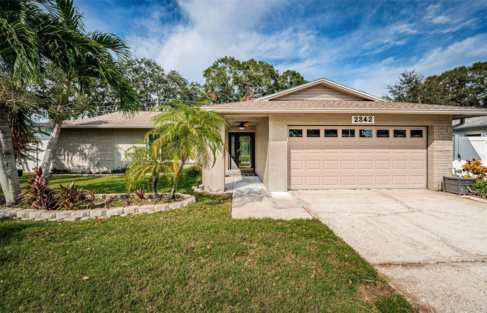 Brand NEW ROOF, fresh paint, new carpet in two bedrooms and Florida Room! Centrally located 3 bedroom, 2 bathroom, 2 car garage home in Woodgate of Countryside offers comfort, peace of mind and privacy! GREAT LOCATION near Countryside Mall with quick access to US 19 and Belcher Rd. SOLID concrete block construction with no immediate rear neighbors and lush tropical landscaping for private back yard gatherings! The elevation of more than 82 feet above sea level and NO EVACUATION zone provide peace of mind! Features include a renovated kitchen with sought-after natural GAS range and a full complement of appliances, eat-in dinette area, wood cabinets, granite counters and under cabinet lighting, not to mention a fan to keep the cook cool and a huge family room with newer vinyl plank flooring and access to the back yard and deck. When you walk in the foyer, a large living room is on the left and entertaining-sized dining room straight ahead. Featuring a desirable split floorplan with 2 large bedrooms and one bathroom on the right and spacious primary retreat to the left of the kitchen. The updated primary suite features a large bedroom, walk-in closet, and en-suite bathroom with large glass-enclosed shower and rich wood cabinet with granite countertop. The sunny Florida room also has an air vent, but is not included in the 1967 sf of living space. The large back yard features lush tropical landscaping and rear easement offering privacy with no immediate rear neighbors. The large concrete slab deck in the expansive back yard is perfect for grilling and entertaining! There is even a quaint gas light pole to gather around. The laundry is located in the garage. Natural gas was added in Dec. 2021 along with a new tankless gas water heater and gas range. HVAC is 2014. Near tons of shopping, grocery stores, banking, bountiful dining options, medical providers, hospitals and public transportation. Approx. 15 -30 minutes to Tampa and St. Pete-Clearwater airports, #1 Clearwater Beach, Caladesi Island, numerous parks & so much more, including the adjacent Woodgate Park with pickle ball and tennis courts, basketball court, playground, pavilions, picnic tables, barbecue grills, paved walking trails and an open playfield. Zoned for great schools! Room sizes are approximate. Not in a flood zone.