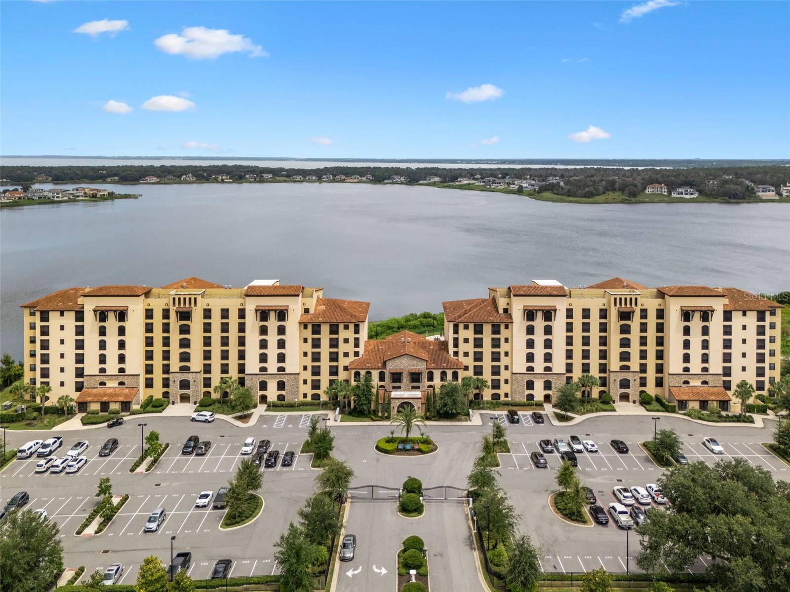 Experience luxury lakefront living in this exquisite 3-bedroom, 3-bath corner unit condo located in the exclusive Siena at Bella Collina. With sweeping views of Lake Siena from nearly every room, this stunning residence offers an unmatched blend of elegance, comfort, and convenience—all within a gated, resort-style community. The thoughtfully designed open floor plan seamlessly connects the gourmet kitchen, dining area, and spacious family room, all oriented to capture the breathtaking lake views. The chef’s kitchen is a showstopper, featuring sleek cabinetry, stainless steel appliances, a tiled backsplash, and a large extended island with a built-in beverage refrigerator and custom storage solutions. Start your mornings on the tranquil, screened-in balcony—an ideal space to unwind and take in the serene surroundings. Luxury upgrades are found throughout the home, including elegant all-tile flooring, plantation shutters, crown molding, custom window treatments, designer lighting, and unique built-in features that elevate the home’s character. The versatile third bedroom is currently configured as a lavish walk-in closet, but can easily be converted back to a full bedroom to suit your lifestyle. Additional highlights include two assigned parking spaces, gated entry with evening security, and access to world-class amenities. Residents enjoy a heated lakefront pool, scenic walking trail, fire pit, BBQ area, poolside seating, conference room, and a 24-hour fitness center. Whether you’re seeking a full-time residence or a sophisticated retreat, this exceptional condo offers the ultimate in luxury, privacy, and panoramic lakefront living. You're also nestled within a well-established gated community, this property enjoys an enviable location close to major highways, ensuring convenient access to all amenities. Just minutes away, residents can indulge in excellent shopping opportunities, dine at a variety of luxury and casual eateries, and explore nearby theme parks for entertainment. The neighborhood benefits from proximity to brand-new, state-of-the-art hospitals and a top notch school system, providing peace of mind for residents seeking quality healthcare services and high end education for their family. This vibrant community offers an abundance of options to suit every lifestyle need and preference. Call today to schedule a private tour.