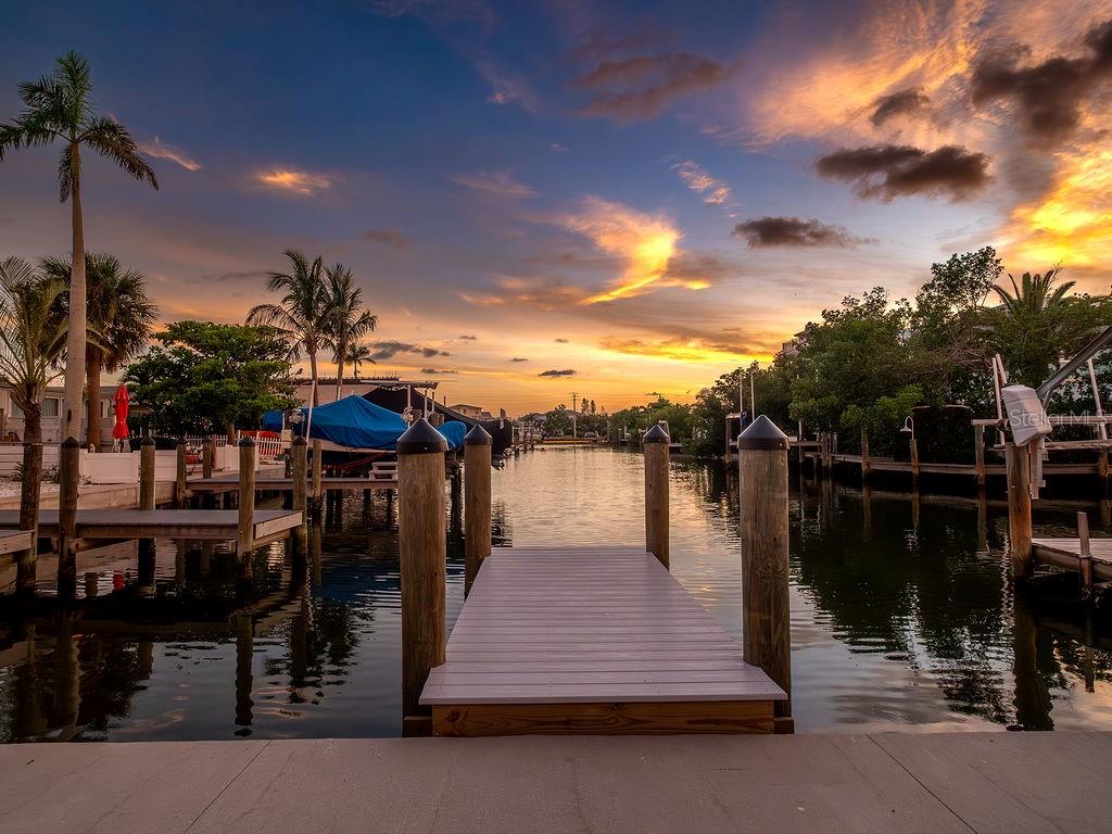 Welcome to this charming 2 bed and 2.5 bath concrete villa located in the heart of Holmes Beach. Offered fully renovated top to bottom this villa has a bright open floor plan and tranquil water views. Features include new bright kitchen with quartz counters, gorgeous baths, luxury vinyl plank throughout, impact windows and doors, new AC, plumbing, electric, roof, and more!
Enjoy the island lifestyle under the oversized covered patio on a sunset facing canal that opens to Watson’s Bayou and the Intracoastal Waterway. New dock, two parking spaces with one car carport and storage shed, too. Historic Seaside Gardens offers a great location with NO HOA. Civic association maintains common areas. Boat ramp, tennis, shuffleboard, pickle ball and the dog park are just steps away. Weekly rentals are permitted, too! This is the perfect slice of paradise!