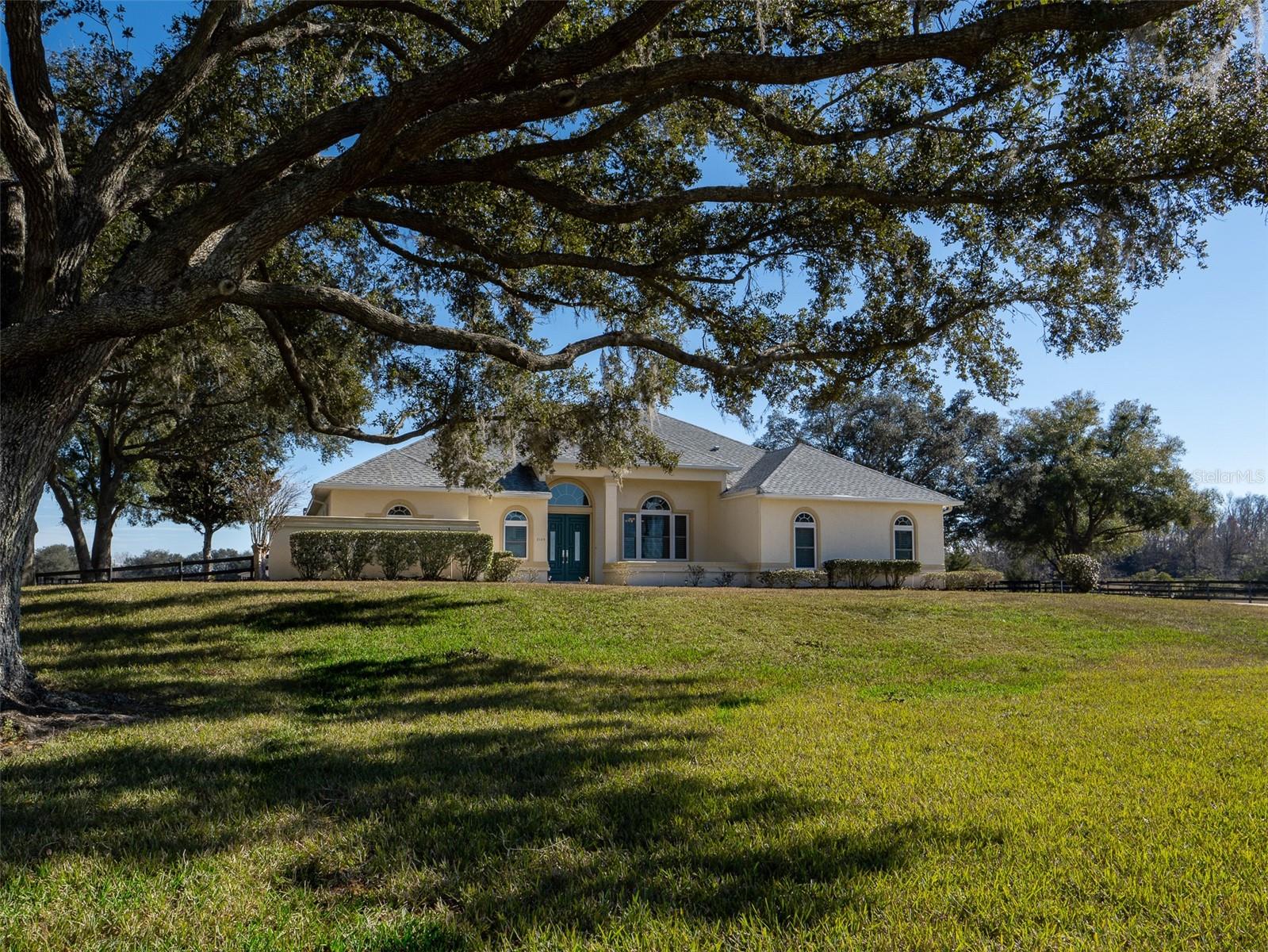 Located in the gated equestrian community of Ocala Downs, with bridle paths throughout, this 13.34-acre horse farm offers a combination of prime location, equestrian facilities, and a comfortable home. Situated just 15 minutes from downtown Ocala and just under 20 minutes from the World Equestrian Center, the property provides a prime setting for those who appreciate both convenience and quality. The farm is fully fenced and adorned with granddaddy oaks. The center of the property features a 10-stall block barn with a center aisle, designed for functionality and ease of care. The barn offers a feed room, tack room, wash rack, and a bathroom, making daily operations smooth and efficient. The property includes six well-maintained paddocks that provide ample space for turnouts, allowing your horses plenty of room to roam and graze. The home on the property is both elegant and practical, offering 4 bedrooms, and 3 full bathrooms. With high ceilings and an open floor plan, the living spaces feel expansive and inviting. The covered back porch, perfect for outdoor gatherings, leads you to the screened, solar-heated in-ground pool which provides a perfect oasis for relaxation on warm Florida days. The perfect blend of function, comfort, and location, this horse farm is waiting for you to make it your own.