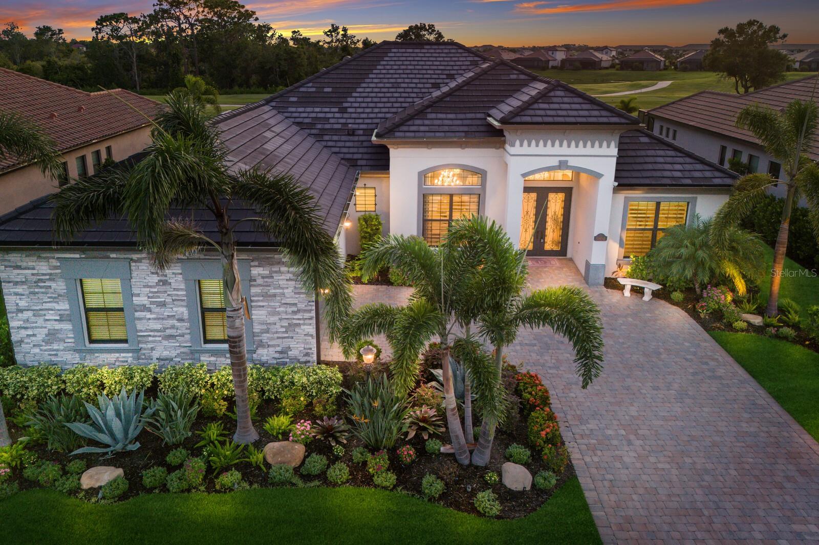 WELCOME to pure ELEGANCE in the highly sought after Lakewood National Golf Club community of Lakewood Ranch! This 4 bedroom, 3 bathroom, 2 car garage home offers 2,776 sq. ft. of impeccably designed living space and is a true SHOWSTOPPER!!! Built by Lennar, this Bougainvillea model has been thoughtfully upgraded with LUXURIOUS finishes and exceptional attention to detail throughout. Step inside and feel the GRAND scale of the open floor plan, where sophistication and comfort meet. The foyer features a custom STONE column and railing, creating a dramatic overlook into the formal dining room, which includes a built-in bar with wine cooler, perfect for entertaining. The heart of the home is the open concept kitchen and living room, where no detail has been spared. The CHEF'S kitchen boasts upgraded cabinetry with custom knobs, QUARTZ countertops, tile backsplash, stainless steel appliances, and a large island with seating. A separate dining nook overlooks the pool, offering a casual space to enjoy meals with a view. Relax in the inviting living room featuring a custom TRAY ceiling, built-in stone fireplace with mantel, and the ideal layout for cozy movie nights or gatherings with family and friends. The PRIVATE primary suite is tucked away on one side of the home and offers tranquil views of the lanai, DIRECT ACCESS to the pool, dual walk-in closets, and a luxurious ensuite bath with dual sinks, a separate makeup vanity, garden tub, and a walk-in tiled shower. Two additional bedrooms are located on the opposite side of the home, providing privacy for guests. One features its own ENSUITE bath with a glass walk-in shower and direct access to the pool, serving as the perfect POOL BATH. A fourth bedroom is ideal as a home office or additional guest space. The laundry room includes custom cabinetry and a sink for added convenience. Throughout the home, you'll find custom tray ceilings, CROWN molding, Schonbek CRYSTAL chandeliers, Pirouette shades, plantation shutters, and designer drapery, all contributing to the home's high-end aesthetic. Step outside to your own private Florida OASIS. The heated saltwater POOL and SPA is enclosed by a PANORAMIC screen, offering STUNNING GOLF course views and unforgettable sunsets. Entertain with ease at the stone outdoor kitchen, complete with stainless appliances and hood. The entire lanai and front entry feature WOOD PLANK ceilings for a MODERN designer touch, and the lanai is finished with pavers. The BEAUTIFULLY landscaped yard includes mature palms, privacy-enhancing shrubbery, and low-voltage lighting, creating a serene and UPSCALE outdoor environment. This is more than just a home; it's a statement of LUXURY, comfort, and timeless ELEGANCE. Lakewood National offers world-class amenities, including TWO Arnold Palmer designed CHAMPIONSHIP golf courses, tennis, pickleball, bocce, a resort-style pool with beach entry and hot tub, a state-of-the-art fitness center, and a full-service salon and spa. The community also features an expansive clubhouse, two restaurants, a tiki bar, dog park, playground, and 24-hour guard gate. Lakewood Ranch is known for its A+ rated schools and is perfectly located just a short ride to downtown Sarasota, St. Pete, world-class shopping, fine dining, and the FAMOUS Gulf beaches. Don’t miss out on this EXCEPTIONAL property that combines luxury living with picturesque surroundings making it truly a golfer’s DREAM. Start living your Florida LIFESTYLE today!!