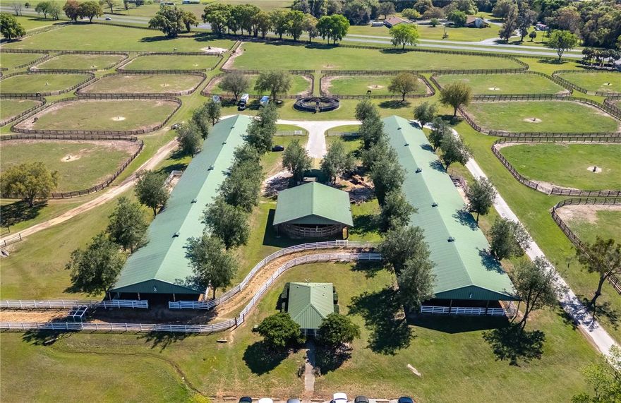 Create your equestrian legacy on this expansive 200-acre established thoroughbred training center with a proven track history of training superior race horses such as Triple Crown Winner American Pharoah and super mares Unbridled Forever and Covefe. This farm was well laid out and has room for future development if desired. Set amid the gently rolling landscape of North Central Florida, this property is a rare opportunity to step into a fully equipped operation with the flexibility to grow. Whether you’re looking to elevate your training program, expand a breeding facility, or build a world-class equine center from the ground up, the groundwork is already in place. At the heart of the property are two expansive 40-stall concrete block shedrow barns, each outfitted with steel roof structures, dual wash racks, and dedicated tack and feed rooms—offering durability, organization, and efficiency for large-scale operations. Complementing these are three 20-stall wooden shedrow barns, each with metal roofing, wash racks, and their own tack and feed areas. A separate 6-stall center aisle barn adds further flexibility for private use, isolation, or smaller groups of horses. Between the 40-stall barns lies a centralized office with restrooms and a laundry room, as well as an equipment barn for added convenience. Training and conditioning facilities abound, including a 7/8-mile gallop track, a 5/8-mile irrigated track, two Eurocizers, and a covered round pen—offering ideal options for every stage of development and performance. A large viewing stand provides a prime vantage point for training sessions or events. With a total of 40 paddocks, each securely fenced in four-board fencing and equipped with automatic waterers, the property offers ample turnout and rotational grazing options. Four wells and five septic systems service the farm, ensuring smooth operations across the board. Additional structures include a Quonset-style hay and equipment barn, further bolstering the property’s functionality. A 3-bedroom, 2-bath split plan home with a garage is already established on-site, ideal for owners, trainers, or staff. The gated entrance and excellent road frontage enhance privacy and accessibility, setting a professional tone from the moment you arrive. Conveniently located just off US HWY 301, this property offers quick access to Ocala and Gainesville, placing show venues, veterinary clinics, tack and feed stores, and other equestrian services within easy reach. From its extensive amenities to its prime location, this is more than just acreage—it’s the foundation for something extraordinary. Additional purchase option available, see OM691626 for more information.
