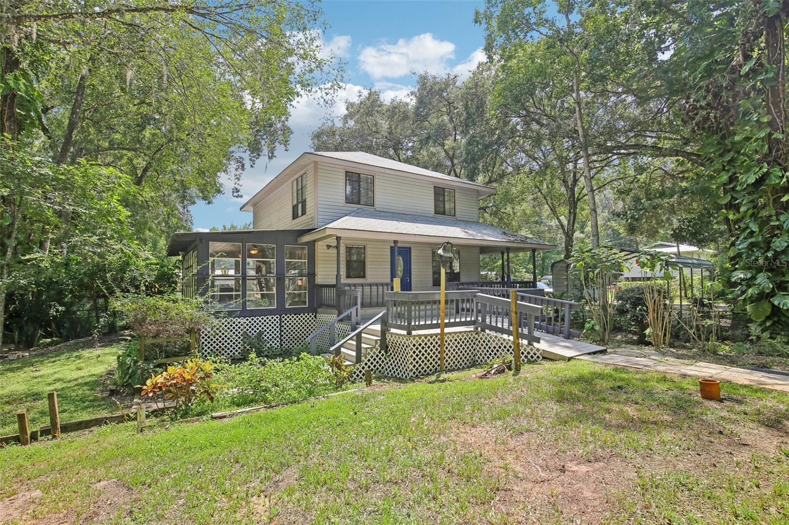 One or more photo(s) has been virtually staged. ***MOTIVATED SELLER*** CALLING ALL NATURE LOVERS! BRING OFFERS AND MAKE THIS PROPERTY YOURS TODAY! Here is your opportunity to own a piece of Old Florida paradise and enjoy the RIVER LIFE! This handsome Victorian Bungalow was CUSTOM BUILT in 1995 and it is located in the small, hideaway community of INDIAN BOW RETREATS, which provides you with deeded BOAT ACCESS to the WITHLACOOCHEE RIVER. Bring the boat, kayak, or canoe and your fishing rods, too! The PRIMARY HOME has so much CHARACTER inside and out, including a stunning WRAP AROUND PORCH, open air deck, LEADED GLASS DOORS, freestanding PROPANE FIREPLACES, and a FLORIDA ROOM that will entice you to spend most of your time there enjoying the wondrous view of the backyard. The .77 ACRE parcel is gorgeously studded with mature trees, bromeliads, and other flowering plants in the LANDSCAPING. The backyard neighbor is a wooded parcel that is home to tons of woodland creatures who live among the canopy of trees. You never know when a deer, fox, or raccoon may stop by to visit! There is plenty of BIRD WATCHING to be done as well, and the symphony of frogs and crickets will let you know when the sun is getting ready to set each day. If you’re an auto enthusiast or you have other land toys, there is room for those here, too! There is a 28x23 STEEL GARAGE with split roll-up doors and a double concrete driveway, and there are 3 ADDITIONAL paved parking spaces under CARPORTS, as well. The SECONDARY HOME (ADU) interior has been completely gutted, so it is currently available for use as ADDITIONAL STORAGE/WORKSHOP space. However, there is TREMENDOUS POTENTIAL to build out the home to serve as a BONUS RESIDENCE (1 Bath Studio Apartment) to allow for a MULTI-GENERATIONAL living or perhaps rental income. This RETREAT ON THE RIVER has so much to offer. Whether you’re looking for a PEACEFUL homestead, RELAXING vacation home, or a GOOD RETURN on investment, this dynamic property can satisfy it all! Call today to claim your piece of paradise at INDIAN BOW!
