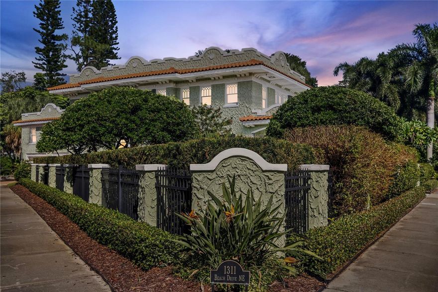 Known locally as The Cake House, this timeless Mediterranean masterpiece is one of Old Northeast’s iconic historic residences, a century-old architectural gem originally designed by the same architect behind Dunedin’s famed Fenway Hotel. On a prized corner lot along picturesque Beach Drive, the home blends Havana-inspired design and 1920s craftsmanship with thoughtful modern luxury updates throughout. Showcasing original interior and exterior brick, refinished hardwood floors, detailed millwork and a distinctive pagoda-style roofline, the property radiates warmth, history and sophistication. Inside, a light-filled tranquil sunroom opens to flexible dining and living areas pre-wired for audio/visual, ideal for entertaining. The main level includes a formal dining room, and a full butler’s pantry with bar functionality off the chef’s updated kitchen, featuring a movable island and period details that honor the home’s heritage. The enclosed laundry room includes a washer and dryer, with an adjacent mudroom and indoor tankless water heater. The luxurious primary suite is a sanctuary of elegance, complete with crown molding, a California closet system, dual vanities, and an oversized walk-in shower clad in Calacatta marble with opulent fixtures and abundant natural light. Guest accommodations are equally inviting, with spacious bedrooms, dual closets, and beautifully updated baths that harmonize with the home’s character. Outdoor living is elevated with a private Mediterranean-style courtyard featuring a custom wood-fired kitchen, gazebo dining pavilion and restored original deck pillars surrounded by lush new landscaping. Every detail invites relaxation and connection. Additional highlights include updated electrical and copper plumbing, new under-home ductwork (2024), a newly installed CPVC water main to the street and ongoing air conditioner maintenance for peace of mind. The detached two-car garage accompanies a fully equipped one-bedroom, one-bath ADU with kitchen, washer/dryer, and private entry, ideal for guests, extended family or income opportunity. Set on a 7,920-square-foot lot in one of St. Petersburg’s celebrated neighborhoods, 1311 Beach Drive NE is a rare blend of architectural authenticity and modern livability. Every improvement has been permitted, curated and meticulously maintained, offering a once-in-a-generation opportunity to own one of Old Northeast’s beloved landmarks.