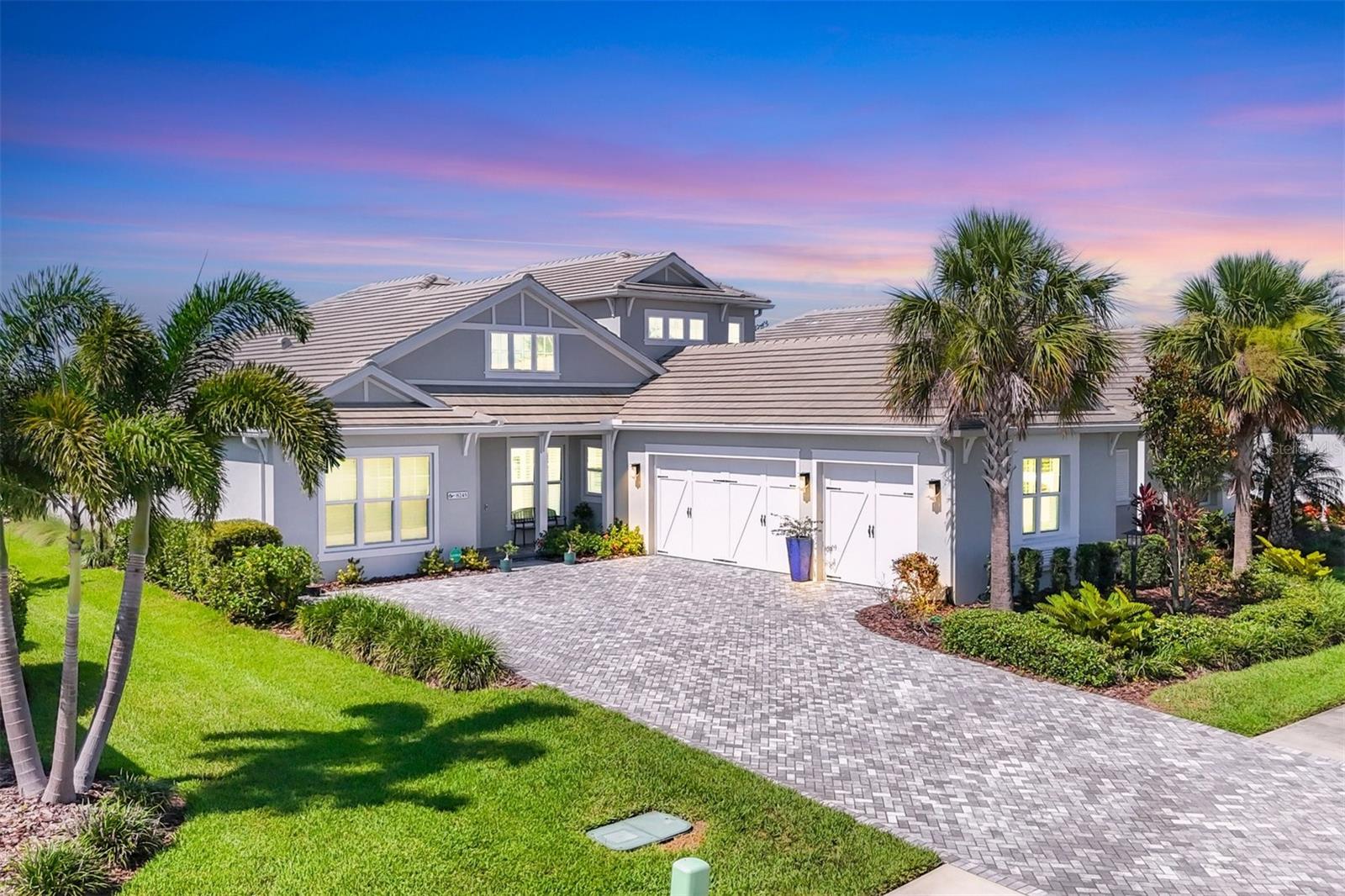 Welcome to your dream home in the highly sought-after community of Lakehouse Cove at Waterside in Lakewood Ranch Florida. This immaculate and one of a kind, custom-designed Tideland model combines contemporary elegance with impeccable craftsmanship, offering the perfect sanctuary for luxurious living and entertaining. Step outside to your heated saltwater pool and spa, adorned with deck jets and a panoramic clear view screen—ideal for relaxing or hosting memorable gatherings. The expansive lanai offers abundant space for outdoor living and dining, complemented by a built-in gas grill and custom cabinets, making every day feel like a vacation. The charming front porch overlooks a peaceful park with water views, setting the tone for the elegance inside. As you enter, you’re greeted by soaring 12-foot ceilings with decorative tray accents, porcelain tile floors throughout the first level, and an array of upscale finishes that elevate your daily living experience. The heart of this home is the oversized chef’s kitchen, featuring top-of-the-line built-in appliances, including a gas range, shaker cabinets with soft-close wood pullouts, and luxurious quartz countertops. The open-concept design seamlessly connects to a spacious dining area and a grand living room with a built-in modern accent wall feature and electric fireplace. Floor-to-ceiling hurricane impact sliders open to the outdoor oasis, blending indoor comfort with outdoor beauty. Wake up to sunlight streaming into the generous primary bedroom, complete with sliders leading directly to the pool. The spa-inspired primary bath boasts dual vanities, a freestanding soaking tub, makeup vanity, and a sleek walk-in upgraded shower—creating a perfect retreat. Custom designer large walk-in closets with built-in organizers maximize storage and style. The front of the home features a secondary bedroom with its own ensuite bathroom and walk-in custom closet—ideal for guests or family. Another first floor bedroom with pool views and a patio slider door. The upgraded laundry room with folding stations and a built-in mudroom bench enhance daily convenience. Upstairs, enjoy a second living area with a built-in kitchenette, an oversized private bedroom with sweeping preserve views, a large custom walk-in closet, and a full bathroom—perfect for guests or family members seeking privacy. Lakehouse Cove offers resort-style living at its finest: a sparkling pool, state-of-the-art fitness center, pickleball courts, a private marina with kayak and canoe launches, and a scenic water taxi to Waterside Place’s vibrant town center. All this within a community designed for leisure, connection, and luxury. Additional Features include a Spacious three-car garage for vehicles and hobbies, Elegant plantation shutters throughout, Enhanced curb appeal with lush landscaping, a Generac whole house generator, new interior paint throughout, custom motorized power window treatments, upgraded HVAC system, wall box Electric Vehicle charger in garage, drop down garage ceiling storage racks and lots of built in custom storage cabinetry, whole home alarm system and security cameras inside and outside of the home, and a upgraded pool/spa LED lighting system. Don’t miss your chance to own this extraordinary home. Contact us today to schedule a private tour and experience firsthand the beauty, sophistication, and resort-style amenities that await you in Lakehouse Cove at Waterside.