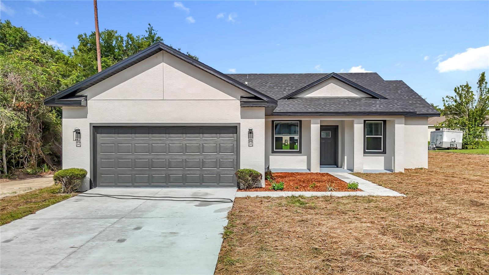 Under Construction. Modern Living Meets Lasting Quality in This Stylish Ocala Home!
Discover effortless elegance in this newly built 4-bedroom, 2-bath home, designed with both style and functionality in mind. Crafted with solid concrete block construction, this residence stands out with its thoughtful layout and upscale finishes, all nestled in one of Ocala’s most desirable and fast-growing communities. Step inside to find luxury vinyl plank flooring throughout—durable, low-maintenance, and beautifully modern. The open-concept floor plan creates an airy, connected space between the living, dining, and kitchen areas, perfect for everyday living and entertaining. The designer kitchen features sleek quartz countertops, premium cabinetry, and a full suite of stainless steel appliances, including a built-in microwave, dishwasher, and range. Eye-catching modern light fixtures and ceiling fans in key rooms add comfort and contemporary charm. The private owner’s suite offers a tranquil retreat, complete with a spa-inspired ensuite bathroom, double vanity, glass-enclosed shower, and generous walk-in closet. Three additional bedrooms are located toward the front of the home, conveniently sharing a stylish full bathroom. Enjoy the convenience of an indoor laundry room with a built-in sink, and extend your living space outdoors with a covered lanai, featuring a built-in sink and hood—perfect for weekend BBQs or relaxing evenings under the stars. Ideally located near top-rated schools, shopping, dining, and major roadways, this home brings together modern luxury, everyday comfort, and unbeatable location. Don’t miss this opportunity to own brand-new in a community where quality and convenience come together.