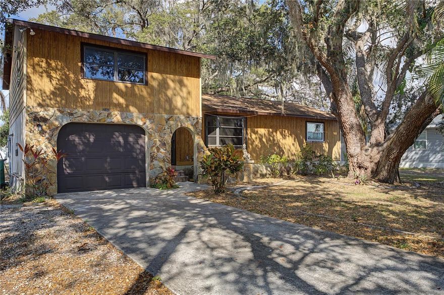 PORT CHARLOTTE HOME W/MATURE OAK CANOPY - Located on a quiet street in Port Charlotte, this 3 bed/2 bath home offers 1,488 square feet of comfortable living space beneath a canopy of mature oak trees. Property is just minutes to shopping, restaurants, medical centers, and everyday conveniences. The exterior showcases unique character with warm wood siding, stone façade accents, and an oversized one-car garage with extended driveway. Towering oaks draped in Spanish moss create natural shade across the front and backyard, giving the property an established, Old Florida feel that’s hard to replicate. Inside, vaulted ceilings enhance the open-concept main living area. Wood-look, laminate flooring runs throughout the living room and bedrooms, while tile flooring in the kitchen and dining areas adds durability. Sliding glass doors lead to a spacious screened lanai with exposed wood ceiling detail, extending the living space outdoors and providing the perfect setting for morning coffee or relaxed evenings under the trees. Kitchen has updated appliances. The split-level layout provides added privacy, with the entire master suite occupying the upper level. This dedicated owner’s retreat includes a spacious bedroom, en-suite bath with walk-in shower, multiple closets, and an additional storage room—offering both separation and functionality. Two guest bedrooms and a full bath are located on the main level. Out back, the backyard offers plenty of space beneath the shade of mature oaks, with existing hardscape areas and room to personalize the landscape. Whether envisioning a garden, firepit area, or expanded outdoor entertaining space, the setting provides a solid foundation. Additional features include an oversized one-car garage with laundry area and no deed restrictions or HOA — giving you the freedom to use the property as you choose. Close to all area amenities including Sunseeker Resort, Charlotte Sports Park (home of Spring Training for the Tampa Bay Rays) as well as downtown historic Punta Gorda and North Port.  If you’re looking for character, privacy, and a prime Port Charlotte location close to everything, this home is ready for its next chapter. Make an appointment today.