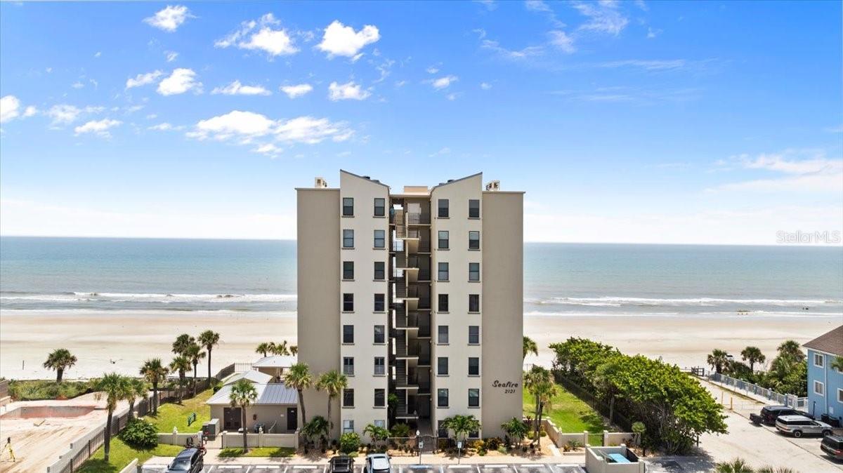 Welcome to Seafire 3A – Where Coastal Chic Meets Oceanfront Elegance! Experience the ultimate beachfront lifestyle in this beautifully remodeled condo located in the exclusive gated community of Seafire. Perched directly on the oceanfront, Unit 3A is an amazing condo where stylish coastal charm blends seamlessly with thoughtful upgrades and timeless design. Step inside and instantly feel a wave of relaxation. The open floor plan, light and bright décor, and unobstructed views of the sparkling Atlantic create the perfect beach retreat. The living space features updated light-wood luxury vinyl plank flooring and elegant shiplap accent walls for a breezy cottage feel. The kitchen is a true centerpiece, featuring stunning granite countertops with creamy tones and turquoise veining, white cabinetry, a glass block backsplash, and a spacious breakfast bar overlooking the dining area and balcony. A cozy yet sophisticated living room centers around a striking stacked stone fireplace—yes, Seafire is one of the rare oceanfront buildings with fireplaces! Flanked by built-in shelving and crowned with a mocha-toned timber mantel, it’s the perfect place to unwind. The primary suite offers tranquility with sunny windows and ample space. The ensuite bath is fully updated with a dual sink vanity, a walk-in shower with modern gray tile, and charming shiplap details. The guest room features a clever Murphy bed system with two beds and added storage, providing flexibility for guests or extra workspace. There is even a trundle bed tucked away in the condo to add even more room for guests. Step out onto your large L-shaped oceanfront balcony and soak in panoramic views of the beach and waves—ideal for morning coffee or sunset cocktails. Additional features include plantation shutters throughout, electric hurricane shutters, and upgraded lighting and ceiling fans. The building has also had recent upgrades such as seawall, landscaping, pavers, renovated pool and elevator system. With a 1-week minimum rental policy, this unit is not only a dream getaway but could also have some income-producing opportunities. Ideally located just east of Atlantic on quiet Hill Street, you’ll enjoy less through traffic and a more peaceful beach experience—while still being just minutes from Flagler Avenue’s restaurants, shops, and vibrant nightlife.