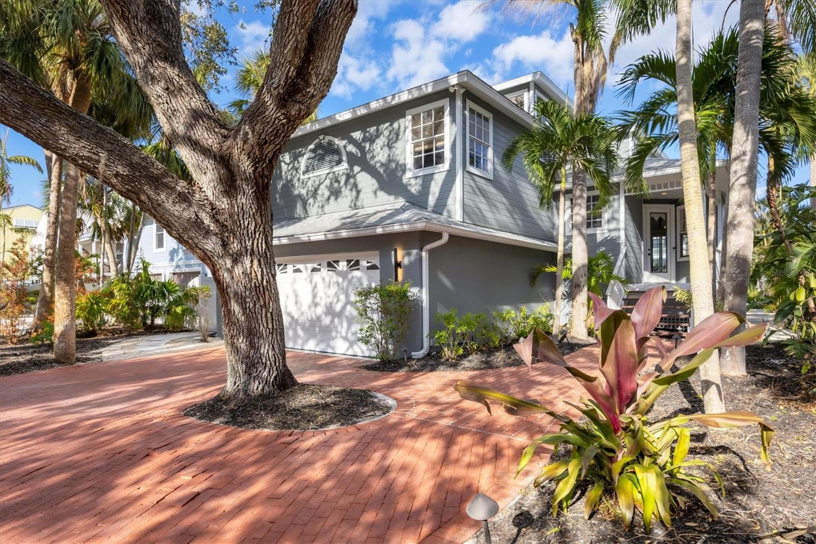 Experience the quintessential Siesta Key lifestyle in this enchanting waterfront home full of Florida charm. 5125 Oxford Road offers four bedrooms, four baths and a two-car garage. Along the Grand Canal beneath a lush canopy of trees, this multi-level retreat ideally balances charm, comfort and functionality. Step onto the covered front porch from the paver driveway and walk-up, and enter through an elegant front door into bright, open living spaces and hardwood floors that extend throughout the main areas. The great room, with its French doors leading to a porch, is a spacious retreat that flows seamlessly into the dining area, where a wall of windows creates a light-filled space ideal for gathering. The adjacent kitchen features a large island with seating, quartz countertops, white cabinetry, a white tile backsplash and white appliances. A versatile sunroom, used as an office, boasts walls of windows and wood floors, making it an ideal space for work or relaxation. Just outside the sunroom, a casual living space with built-ins offers additional functionality. The home’s thoughtful layout includes a guest bedroom with and full bathroom on the main floor, a second guest suite with a private bath on the second floor and the primary suite alongside a third guest bedroom on the third floor. The primary suite features built-in storage, wood floors and French doors opening to a private terrace with serene water views. Its spa-like bath includes a freestanding soaking tub, a glass walk-in shower, dual sinks and tile floors. Outdoors, a stone paver deck surrounds the pool and spa, creating an inviting space to relax and take in the water views. For boating enthusiasts, the private deep-water dock, equipped with water, electricity, recently replaced pilings and a 10,000-pound lift, offers direct access to Sarasota Bay, the Intracoastal Waterway and Gulf of Mexico. With its ideal location just moments from Siesta Key Village, the beach and downtown Sarasota, this home delivers an unparalleled blend of island living and modern convenience.