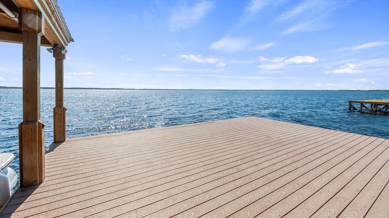 A RARE AND EXTRONDINARY OPPORTUITY AWAITS YOU WITH TIMELESS ELEGANCE AND COMFORTABLE LIVING WITH THIS 4 BEDROOM/4 BATHROOM DIRECT LAKE FRONT HOME ON THE CLERMONT CHAIN OF LAKES. With approximately 3220 sq ft of luxury living this 2019 home combines the finest of finishes with multiple upgrades. This home offers an open airy floor plan with lots of natural light and panoramic lake views of Lake Louisa for your enjoyment, and is perfect for entertaining family and friends. As you walk through the front door you will be greeted with a large great room adorned with high ceilings, a gas stone fireplace, luxury vinal plank flooring, Cypress accents, a gourmet kitchen, large windows, and pocket French Doors leading out to of the lake and boat house. The gourmet kitchen which flows seamlessly into expansive open living areas, is equipped with plenty of upgraded wood cabinets with pull out drawers, a large center island, luxury high end Dacor Appliances which are designed for style and efficiency. The Dacor built in column refrigerator also boasts a large freezer and icemakers. Baking and cooking gourmet meals are made easy with this Dacor 6 burner gas stove with an electric griddle, a dual oven that boasts a bread baking oven, and a food warmer. The formal dining room with views of the lake adds extra dining seating for those special occasions with family and friends. As you move through the home you will notice the tongue and grove and shiplap Cypress walls and accents, which makes this home especially stand out above the others. The downstairs bedroom with a large walk-in closet can be also used as a Primary Bedroom. The bathroom has a tiled walk-in shower, stone counter tops, luxury vinyl flooring. The downstairs office is large, and can accommodate 2 desks or a seating area. There is a door that leads outside the large laundry room with a connecting bathroom with Stone counter tops and walk in shower. The Crown Jewel is the owner’s Primary Retreat, boasting a seating area with a gas fireplace, dual closets, and French doors leading to your private relaxing screened balcony overlooking the lake with beautiful sunsets and sunrises, and cool breezes. Moving into the Primary Bathroom hosts a claw foot ceramic bath tub, his and her sinks, and large walk-in shower. To finish the upstairs, you will find 2 other bedrooms, 1 bathroom with tub & shower combo, and a flex room overlooking the lake that can be used as an office, nursery, man cave, den, the choice is yours. If you are looking for outdoor living this home has it. The outdoor features include, Composite wrap around porch with Cypress Ceiling, storage area with seating overlooking the lake with sink, fire pit, beach, sea wall, 2023 New boat house with electric and water, composite walkway deck, New Wrap Around Deck, New Water Purification System, New Sprinkler System, Gutters and Gutter Drains, New Curbing Around the Home, New Landscaping. 2025 New Septic Pump and Septic pump out. This residence offers elegant design, functionality, and stunning waterfront living, with skiing, boating and fishing on a 3600 Acre Lake which is the largest on the Chain. This home is the perfect format for modern day relaxing, enjoyment, and living.