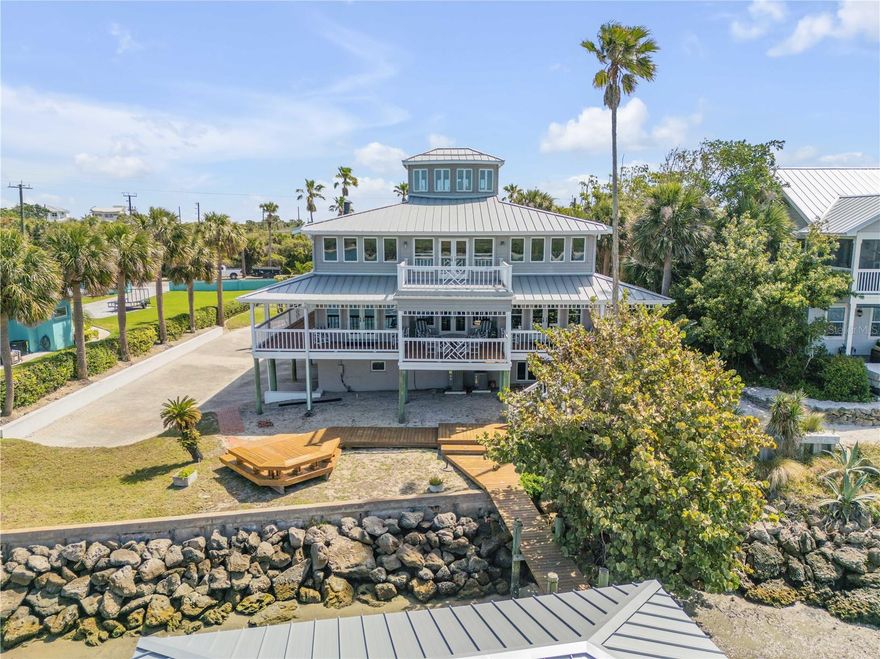 Casually Elegant Florida Coastal Living awaits in this Direct Intracoastal Front Home on New Smyrna Beach’s coveted N. Peninsula Ave. Only minutes to the Inlet. You can’t get a better location than this! “Key West” Style custom home with wide Western and Intracoastal Views. Covered wrap-around porches and a Crow’s Nest where you can enjoy Ocean, River, Sunrise and Sunset Views. As you enter this stunning home your attention goes immediately to the incredible water views and open spaces. Your attention will quickly turn to the center piece of this home, the spectacular Florida Pine Staircase winding from the ground floor through the main living level and up two more levels to the Crow’s Nest. On the Main level you’ll find an open floor plan and gracious living spaces facing the water and opening onto a wide, river front porch. The living room is two stories high and streaming with light. Both the living and dining areas open directly onto adjacent outdoor living spaces, making this home perfect for entertaining family and friends. A very large kitchen flows from the dining area. The kitchen features solid wood cabinets and a DCS gas range and custom range hood. Adjacent to the kitchen is one of two laundry areas. The kitchen offers a breakfast bar and its own large river front breakfast/dining area opening onto the river front covered porch. The main living level also includes two spacious guest rooms and two full bathrooms. Up one flight, you’ll find a breathtaking and spacious loft with wide plank pine floors, spectacular views and an adjacent river front deck. On the South side of the Loft is the large river front Primary Suite. Waking up in this space every day is its own special gift. The ensuite primary bathroom features pine floors, a claw foot tub, a separate walk-in shower and an adjacent walk-in closet/laundry area.  On the North side of the Loft is the 4th bedroom which is also perfect as a home office compliment to the Primary Suite. Up one level is the Crow’s Nest with 360 degree views - from Full Ocean to Full Intracoastal. As if all this is not enough, there is a large Game/Billiard Room on the ground floor complete with wet bar. On the ground level you’ll also find a huge two bay garage with a full bathroom, workshop area and separate 200 sq. ft. (+/-) storage room complete with built-in shelving. This gorgeous home enjoys privacy from the street, sitting on a huge 120' x 235’ Intracoastal Front Property. Offered largely furnished, some pieces are excluded. All Art is excluded unless otherwise negotiated. Concrete sea wall fortified with rip-rap. You’ll enjoy the views and security afforded by the Andersen casement windows. Metal Roof new in 2022. Exterior "Hardie Board” and Painting project complete in 2023. Three Separate Lenox A/C units all new in 2023. The existing dock includes open dock space and a covered boat slip. Seller makes no representations about the condition of the dock, pilings and/or lift, all of which will need attention by the new owner. A great opportunity to create the dock that suits your specific needs.  Be sure to check out the photos and Virtual Tours / Videos to fully appreciate this special home and spectacular location.