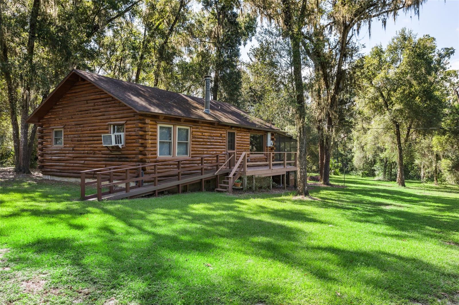 LOG CABIN ON 3 ACRES. Escape to peace and tranquility with this charming 2-bedroom, 1-bath log cabin nestled on 3 acres at the end of quiet Friendly Road. Built in 1982 and meticulously maintained by its longtime owner, this home offers timeless craftsmanship and the serenity of nature all around. Step inside to discover VAULTED CEILINGS that enhance the spacious open layout, where the kitchen and living room flow seamlessly together. The kitchen features a double stainless-steel sink, built-in wall oven and an island cooktop, while the spacious family room offers a cozy WOOD-BURNING STOVE—perfect for cool and crisp evenings. The full bath includes a convenient tub/shower combo. A highlight of this retreat is the EXPANSIVE SCREENED PORCH with skylights, your personal “theater room” overlooking the surrounding wildlife and natural beauty. Here, mornings bring birdsong, and evenings offer a front-row seat to the sounds of nature and spectacular sunsets. Beyond your doorstep and part of this property lies SPRING LAKE PRAIRIE, a pristine 42-acre freshwater seasonal lake surrounded by lush vegetation, connecting you with abundant birdwatching and occasional fishing. The picturesque drive to the property takes you through rolling hills and expansive farmland, setting the stage for a lifestyle that feels worlds away yet close enough to modern conveniences. DOWNTOWN BROOKSVILLE, Florida, is a charming area known for its historic architecture, vibrant community, and outdoor recreational opportunities. The downtown features a mix of quaint shops, museums, and beautifully restored buildings, reflecting the town's rich history dating back to the 1840s. Visitors can explore the May-Stringer House Museum and the Hernando Heritage Museum, which provide insights into the area's past, including its ties to the Civil War. The Withlacoochee STATE FOREST is nearby, providing ample opportunities for hiking and enjoying nature. Downtown Brooksville also hosts various events and festivals, making it a lively place to live. Overall, Brooksville combines the allure of history with modern amenities, making it a unique destination for both residents and visitors. This log cabin property is ideal as a PRIMARY RESIDENCE for those seeking everyday serenity, or as a SECOND-HOME getaway where you can truly unwind, recharge, and embrace peaceful downtime. Don’t miss this RARE OPPORTUNITY to own this ONE-OF-A-KIND log cabin retreat where privacy, nature, and timeless charm come together.