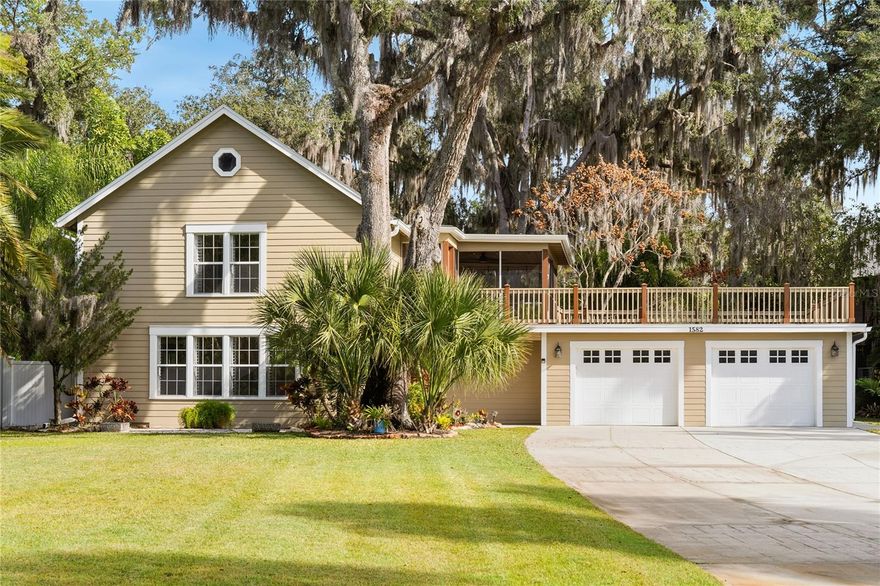 One or more photo(s) has been virtually staged. As you travel down the tree-lined streets beneath a canopy of majestic oak trees, you arrive at one of Enterprise, Florida’s most exclusive and distinctive communities—Stone Island. Known for its individuality and Old Florida charm, this remarkable enclave features custom-style homes where no two residences are alike. Upon arrival, you are immediately captivated by the character of this home, beautifully framed by mature, towering trees. French glass doors welcome you into the casual living room, where travertine flooring and plantation shutters bathe the space in natural sunlight, creating a warm and inviting atmosphere. The galley-style kitchen showcases custom maple cabinetry with crown molding, mirrored accents with open shelving, and exotic Nacarado granite countertops offering generous preparation space. A stainless-steel appliance package completes the kitchen, which flows seamlessly into the casual dining area accented by a built-in buffet and serving station with elegant glass-front cabinetry. The first floor also offers a versatile office or potential fourth bedroom, a mudroom, a spacious laundry room with built-in cabinetry and an oversized storage closet, along with a conveniently located guest half bath. All major components of the home have been thoughtfully updated, including windows and doors, the HVAC system, and the roof, and the property is protected by a termite bond—providing peace of mind for years to come. Follow the wood-lined staircase to the second floor, where a welcoming landing leads to the private living quarters. The owner’s suite features parquet flooring, a large walk-in closet, and expansive windows that fill the room with natural light. The ensuite bath is appointed with rich mahogany cabinetry, tiled countertops, dual framed mirrors, and a modern, luxurious shower with decorative neutral tiles, a built-in sitting area, dual shower heads, and a shampoo niche 
The secondary bedrooms are generously sized and share a fully updated bath with a furniture-style gray vanity topped with marble, along with a tub/shower combination accented by sleek gray subway tile and oversized shower heads. The owner’s suite and guest bedrooms open to a screened lanai and an impressive 725-square-foot rooftop deck, offering a peaceful retreat to relax while taking in tranquil wooded and lake views. Double glass doors lead to an open-air patio paved with red brick pavers overlooking a serene backyard filled with lush Old Florida landscaping. A cobblestone path guides you to a storage shed with a steel roll-up door, electricity, and full fencing—ideal for storing jet skis, trailers, or a john boat. The oversized two-car garage (26’ x 25’) easily accommodates large vehicles, while the extended driveway provides ample guest parking. Located in one of the most captivating areas of Stone Island, this high-and-dry homesite has a clean history and has never flooded. Stone Island is a golf cart–friendly community offering private roads, a boat ramp with access to Lake Monroe & the St. Johns River, tennis and pickleball courts, equestrian stables, a community pavilion, firepit, playground, and easy access to nearby trails. Whether enjoying sunrise fishing or sunset cruises, boating enthusiasts will appreciate convenient access to Florida’s iconic waterways. This tranquil island oasis offers the perfect balance of privacy and convenience, just minutes from shopping, dining, and a scenic drive to I-4 along the north shore of Lake Monroe