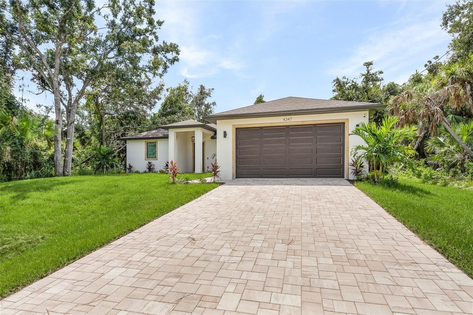 Dori Homes Group proudly presents this stunning and unique newly constructed home. Situated on a a beautiful lot. Designed for comfortable and peaceful family living, the home features 1,610 square feet of living space with three bedrooms and two bathrooms. The property includes a total of 2,305 square feet under cover, comprising a generous living area with ample closet space, a double car garage, a large entrance area, and lanai. The driveway, footpath, and entrance areas are beautifully paved. Additional exterior features include front gutters. Large impact windows and sliding glass doors by ESW flood the interior with natural light. The kitchen is a chef's dream, featuring stainless steel appliances, upgraded cabinets with 42-inch wall cabinets, soft-closing hardware, and crown molding. Quartz countertops with a full backsplash and a large kitchen island with a breakfast bar complete the culinary space. The master suite offers a his and hers vanity and an oversized, fully tiled walk-in shower with a large rain head and hand held shower. The home is adorned with contemporary ceiling fans and chandeliers throughout, and equipped with a smart garage door opener with Wi-Fi for added convenience. High-end luxury vinyl tile flooring runs throughout the house, complemented by contemporary square baseboards and door casings, and color-matched hardware and fixtures. This home blends modern convenience with comfortable living in a spacious and well-appointed setting.