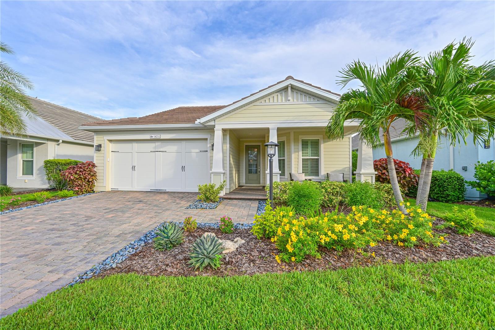 Welcome to Lakehouse Cove at Waterside, where luxury living meets vibrant community. This coveted Cay plan, enhanced with an upgraded craftsman elevation and inviting front porch, offers the perfect blend of style and comfort. Step inside to a dramatic foyer with 11-foot tray ceilings and custom trim details that echo throughout the home. A versatile den provides the ideal space for a home office or flex room, while the expansive great room impresses with soaring 14-foot vaulted ceilings, custom beam detail and seamless flow to the covered lanai. The gourmet kitchen is a true centerpiece, featuring Cambria quartz countertops, designer cabinetry, a large pantry, and open sightlines to the main living area - perfect for both everyday living and entertaining. The primary suite is a serene retreat with an oversized window framing garden views, a tray ceiling with custom detailing, an ensuite bath with dual vanities, a walk-in shower and a spacious custom built closet. A comfortable secondary bedroom and bath provide privacy for guests. Thoughtful details continue throughout: hardwood flooring, plantation shutters, a mudroom with custom cabinetry, a laundry room with indoor storage room and an oversized two-car garage with dedicated golf cart space. Outdoors, the covered lanai beckons with a custom outdoor kitchen and tranquil views of the landscaped yard, serene pond and fully fenced lawn. Additional highlights include impact windows for peace of mind and numerous designer upgrades. Life at Lakehouse Cove means more than just a beautiful home - it's a lifestyle. Enjoy 6 pickleball courts, a resort-style pool and spa overlooking Lake Kingfisher, a state-of-the-art fitness center, boathouse with kayak launch, 2 dog parks, community club house and fire pits where neighbors gather for breathtaking sunsets. Just a short stroll brings you to Waterside Place, brimming with shopping, dining, a weekly farmer's market and year-round events. This fully furnished home (excluding wall art) combines designer touches with resort-style living - an extraordinary opportunity in one of Sarasota's most desirable communities.
